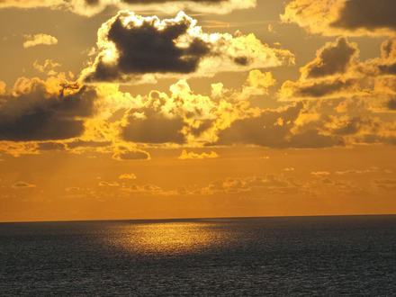 Golden sunset over the ocean with dark clouds and sunlight reflecting on the water