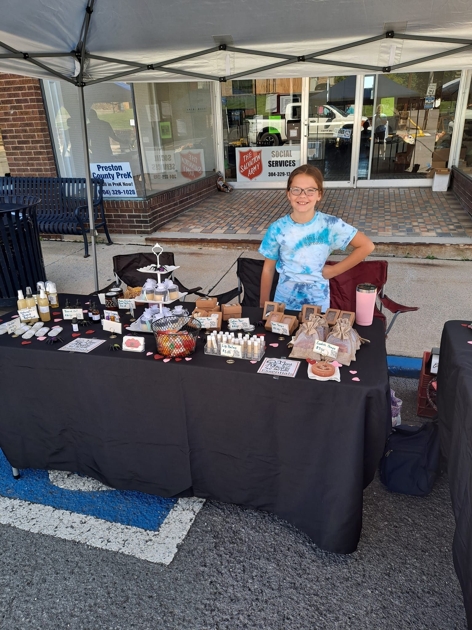A young girl is standing in front of a table with a lot of items on it.