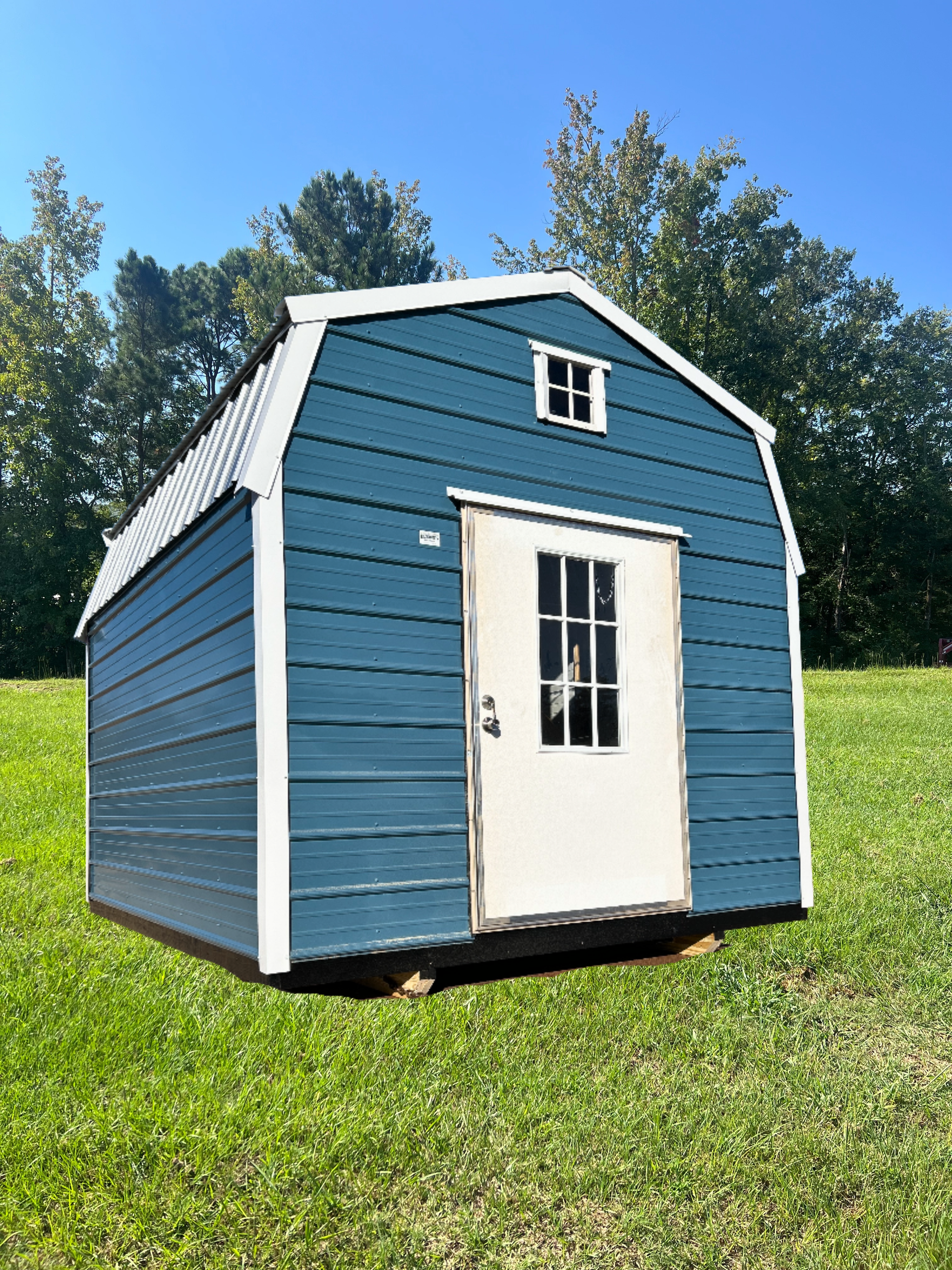 Blue garden shed with white trim and door on a grassy lawn under a clear sky