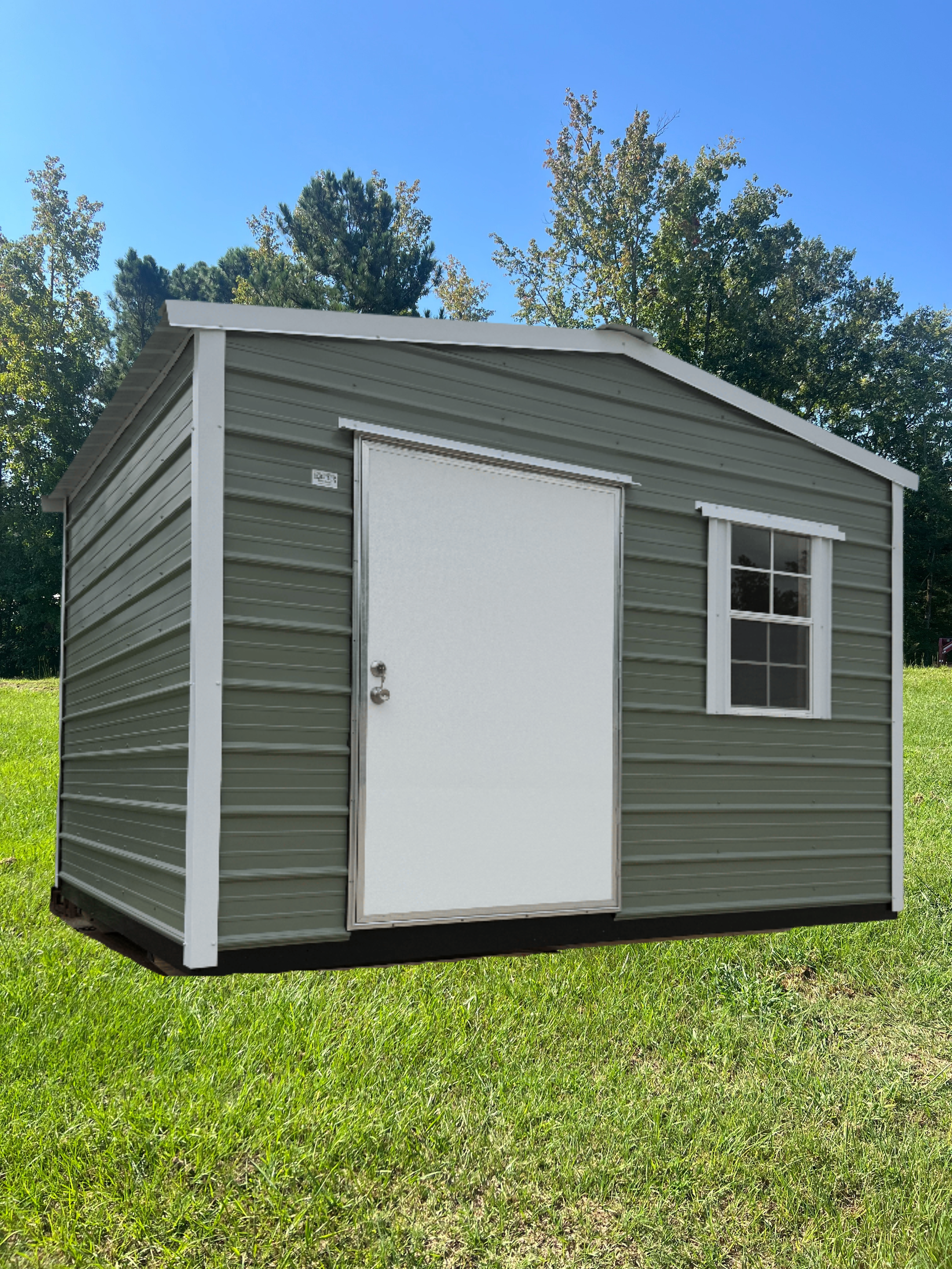 GrEEN outdoor shed with white trim, a white door, and a window on a grassy lawn under a blue sky