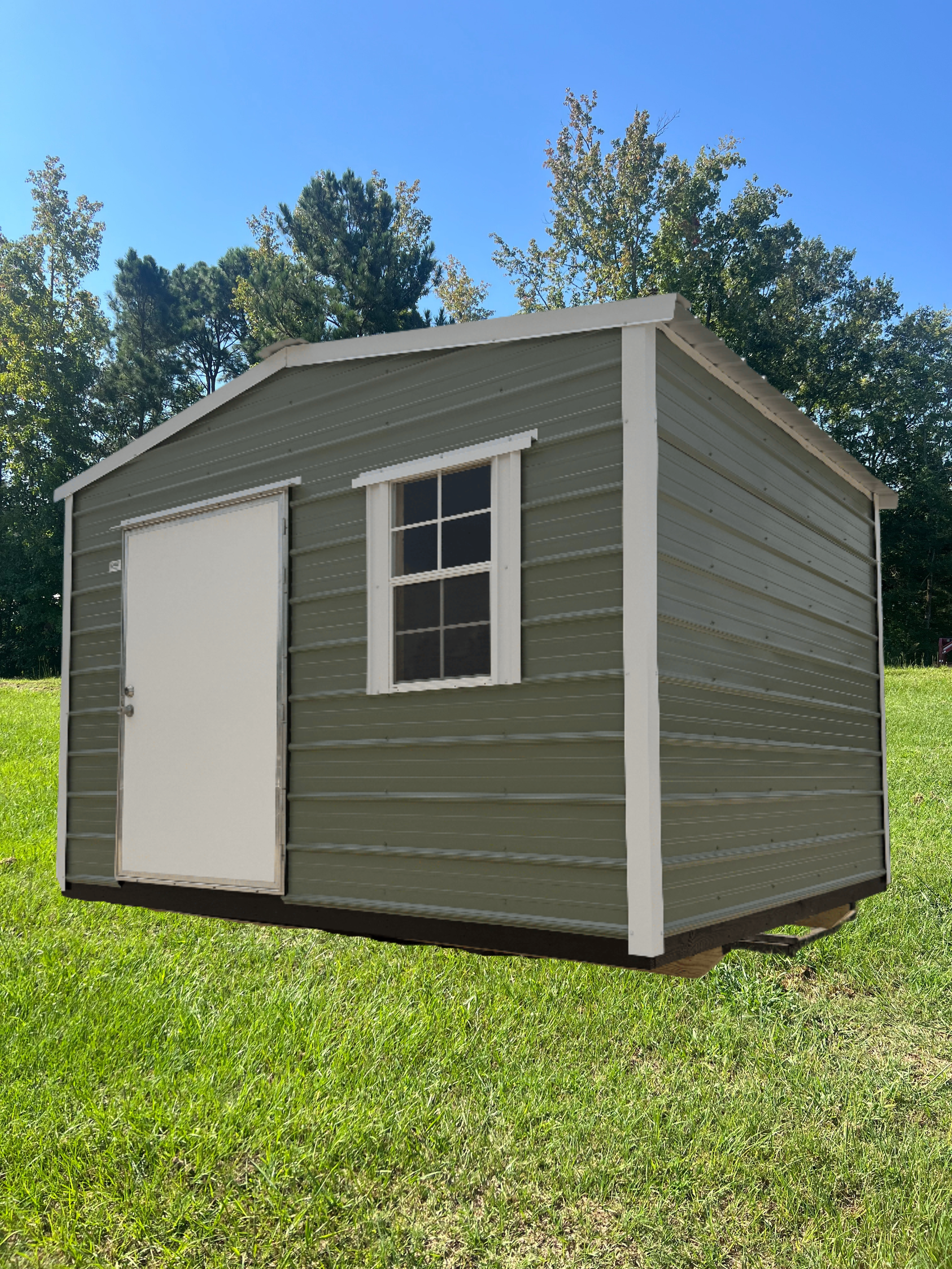Small green shed with white door and window on a grassy lawn under a blue sky