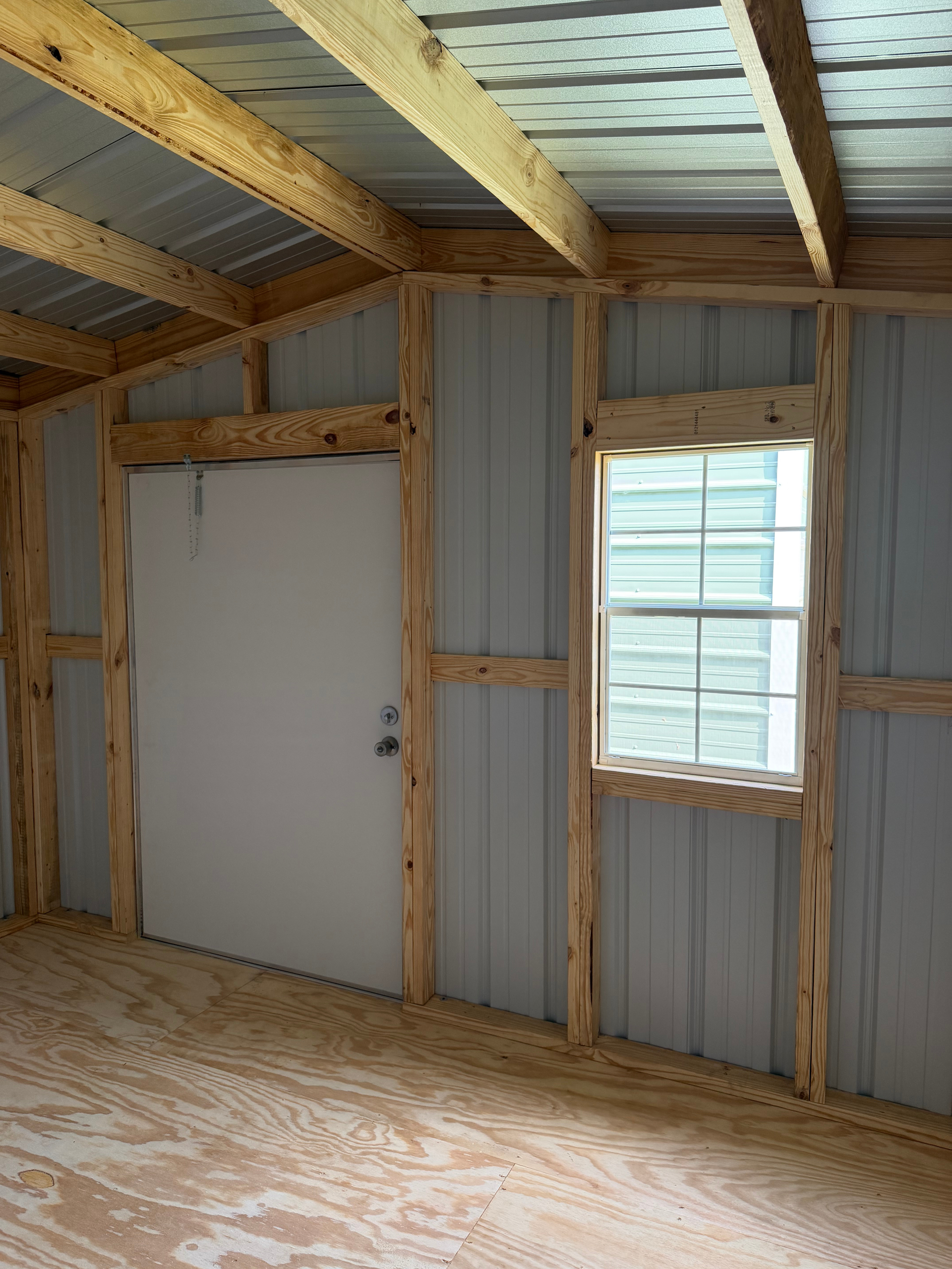 Empty unfinished shed with plywood floor and corrugated metal walls and roof