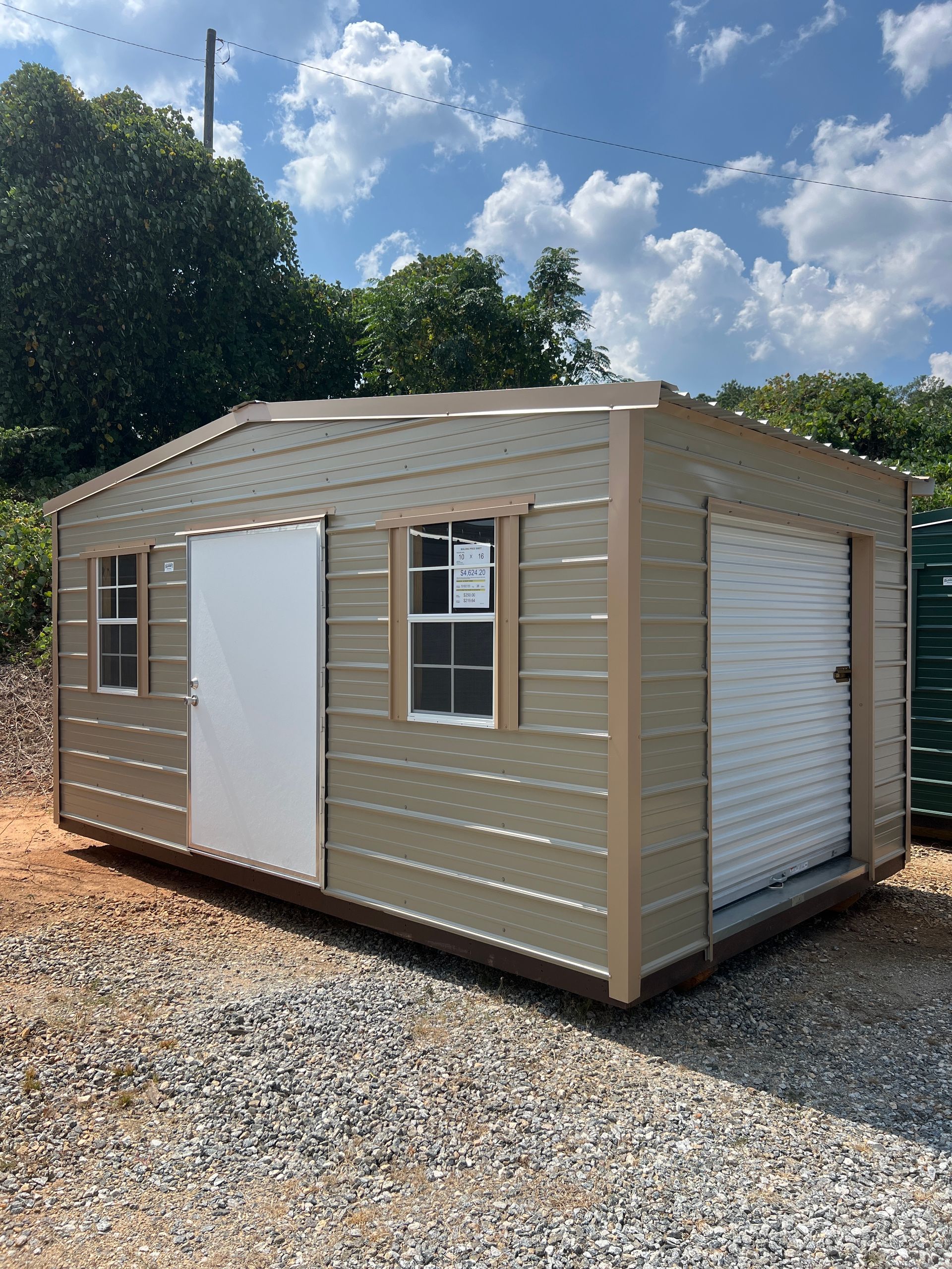 Tan metal shed with two doors and a window, set on gravel, against a partly cloudy sky.