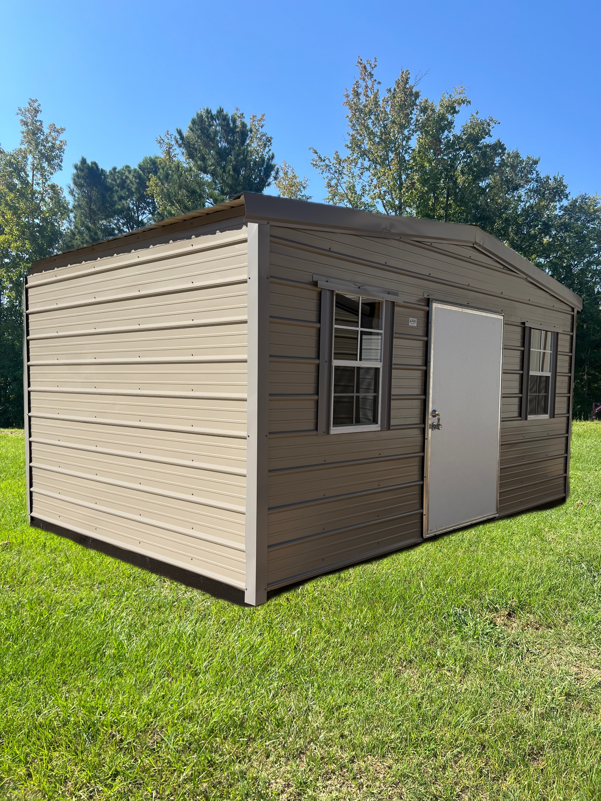 Small beige shed with white door and windows sitting on a grassy lawn under a clear blue sky
