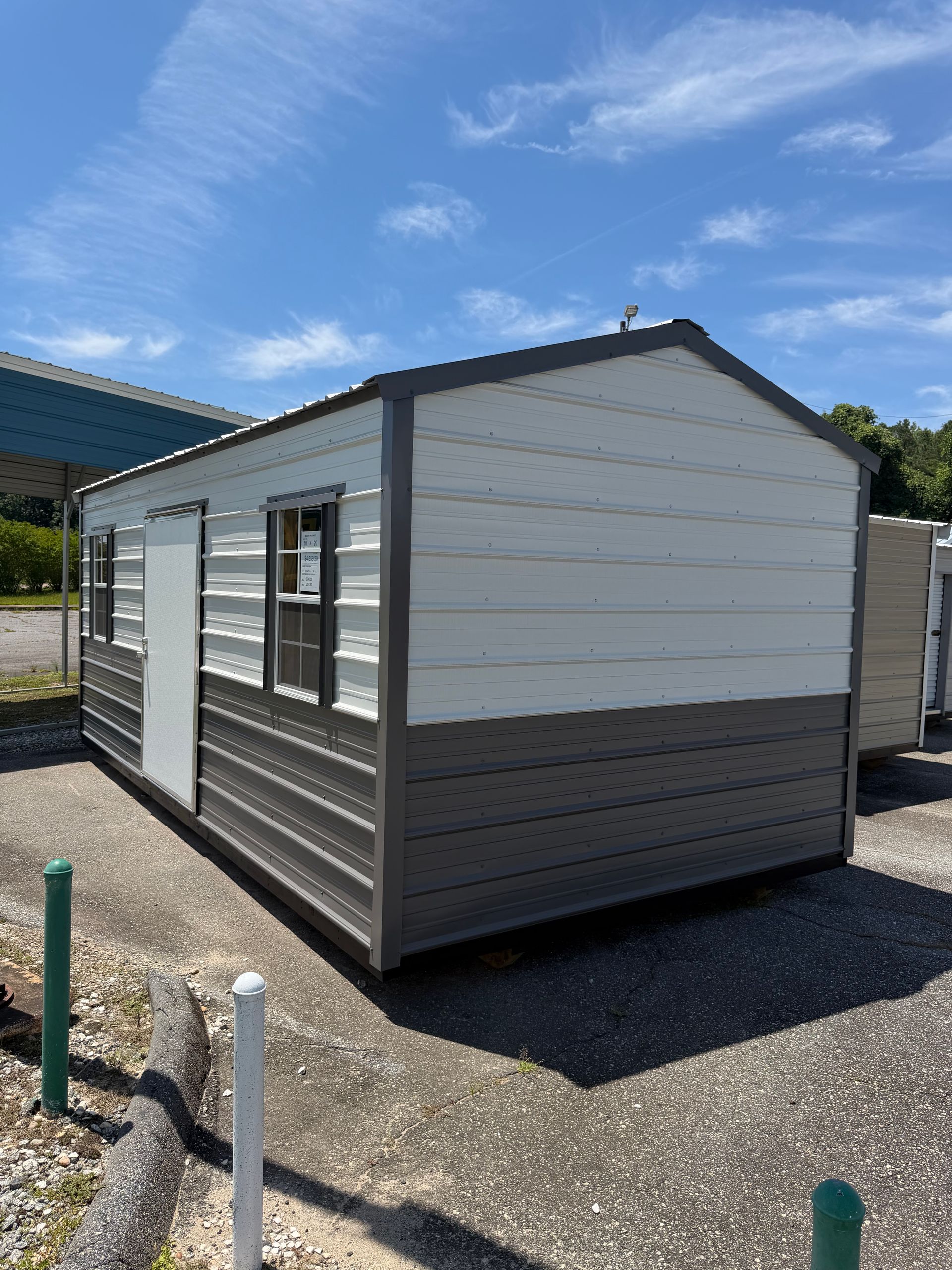 Small white-and-gray portable cabin on gravel under a blue sky