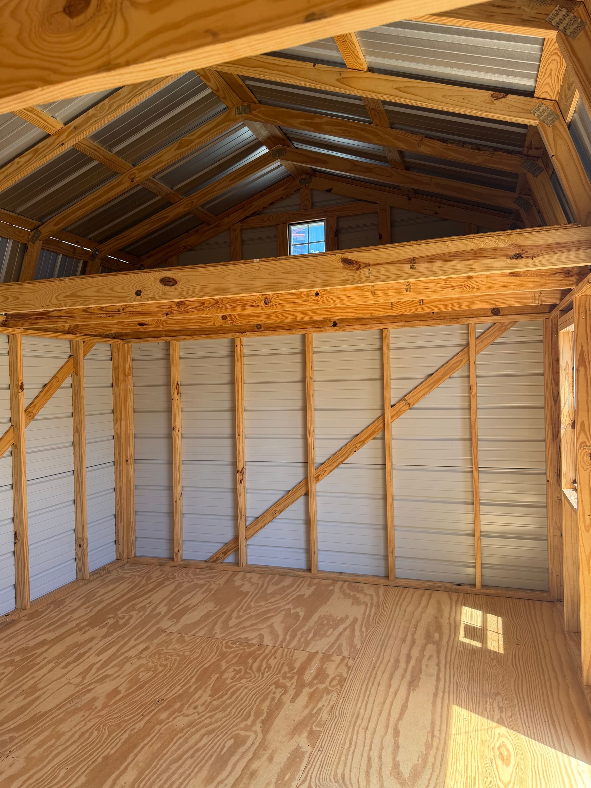 Interior of an unfinished wooden attic with exposed rafters and plywood floorboards