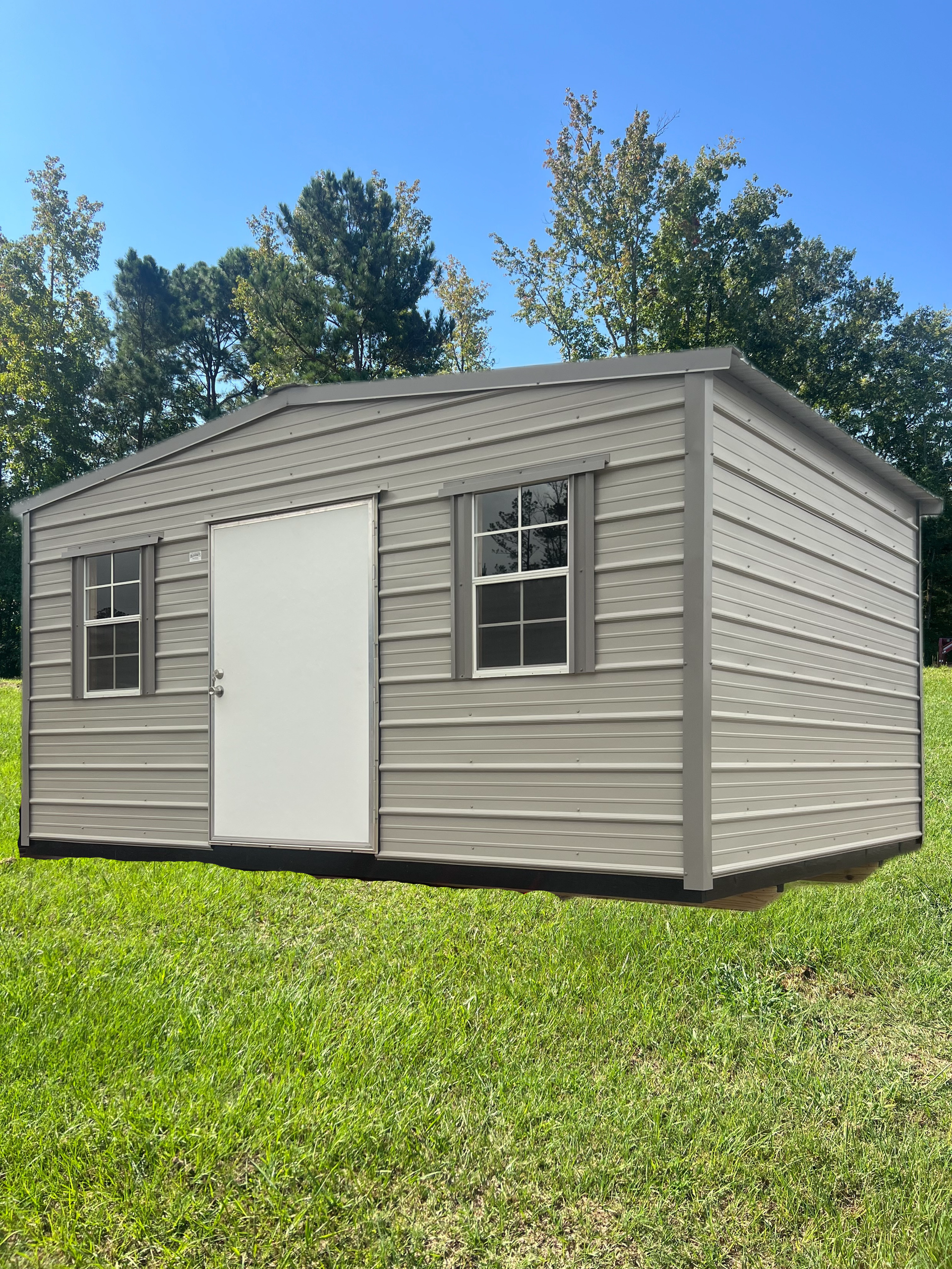 Small gray and white modular building with windows on a gravel lot