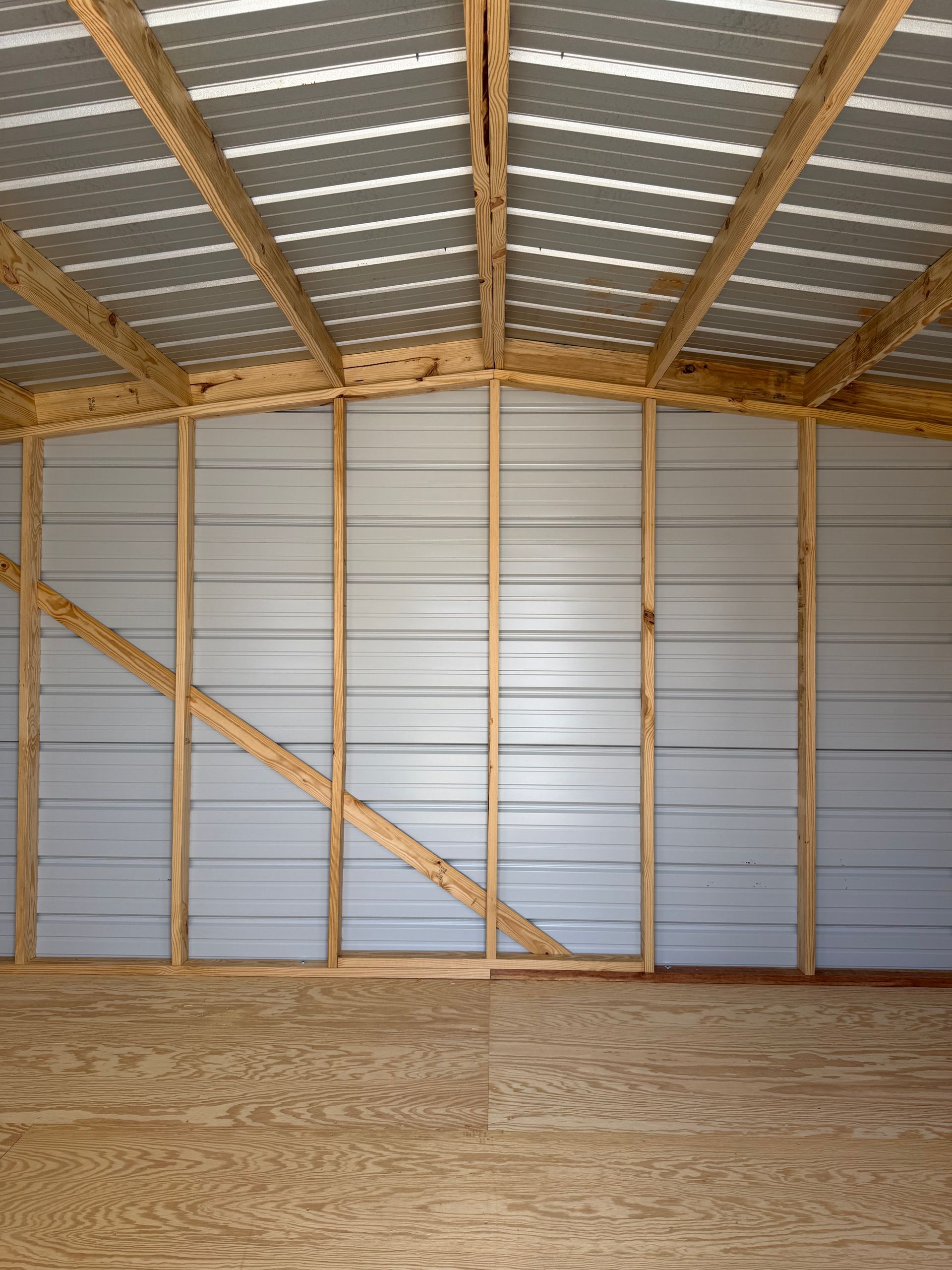 Empty wooden barn interior with metal siding and exposed roof beams