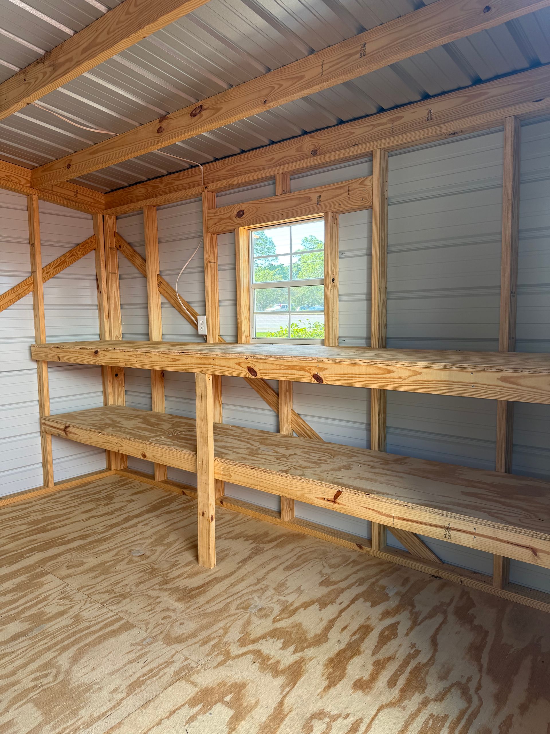 Small unfinished shed interior with wooden shelves, corrugated metal walls, and a window.