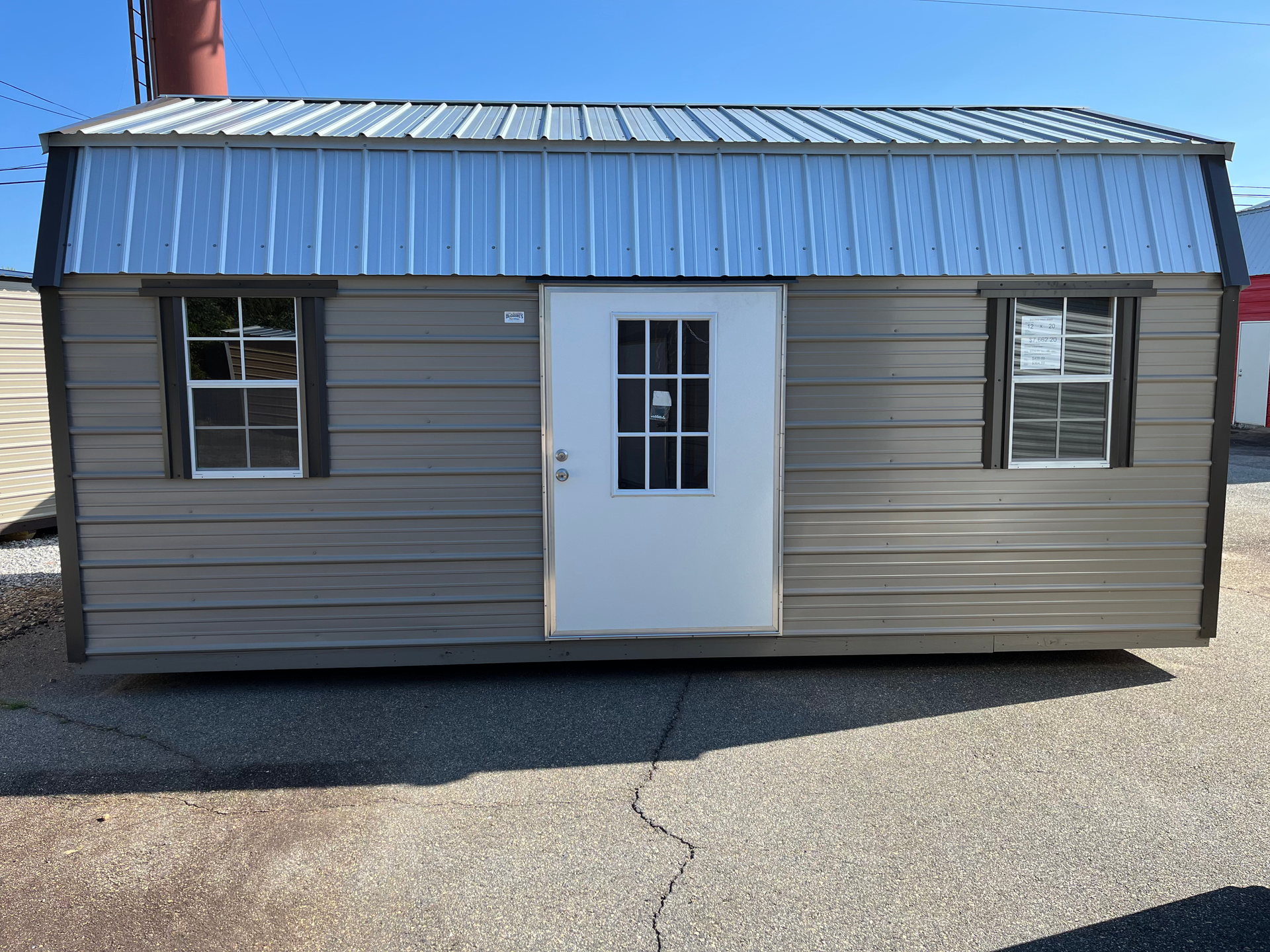 Small beige and blue metal building with a white door and windows on a paved lot