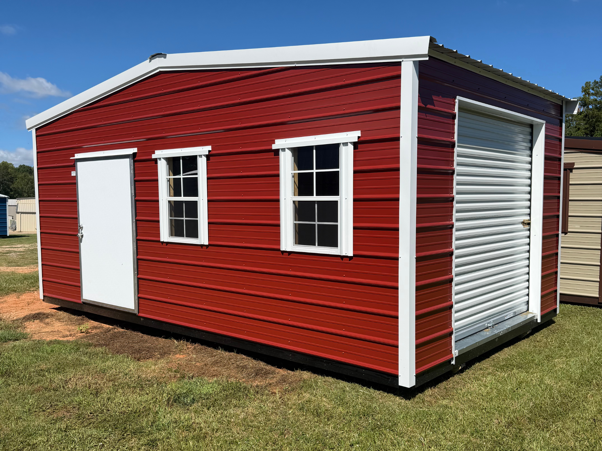 Gray mobile home with a small covered porch and railings on a gravel lot under a blue sky