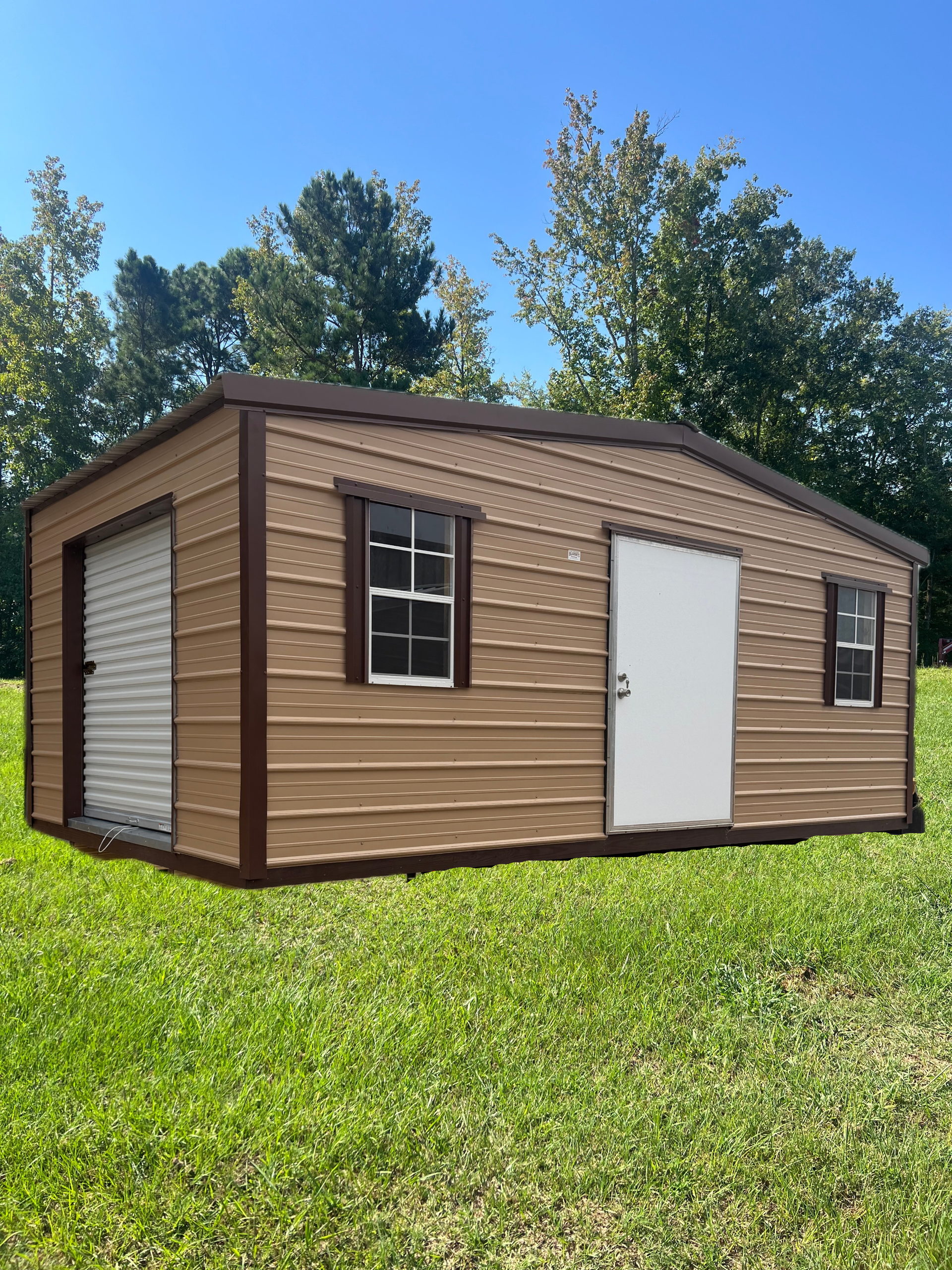 Small tan shed with white door and dark trim on a grassy lawn under blue sky.