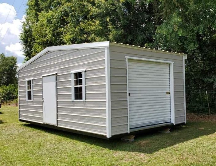 Gray metal shed with a roll-up door, door, and two windows in a grassy setting.