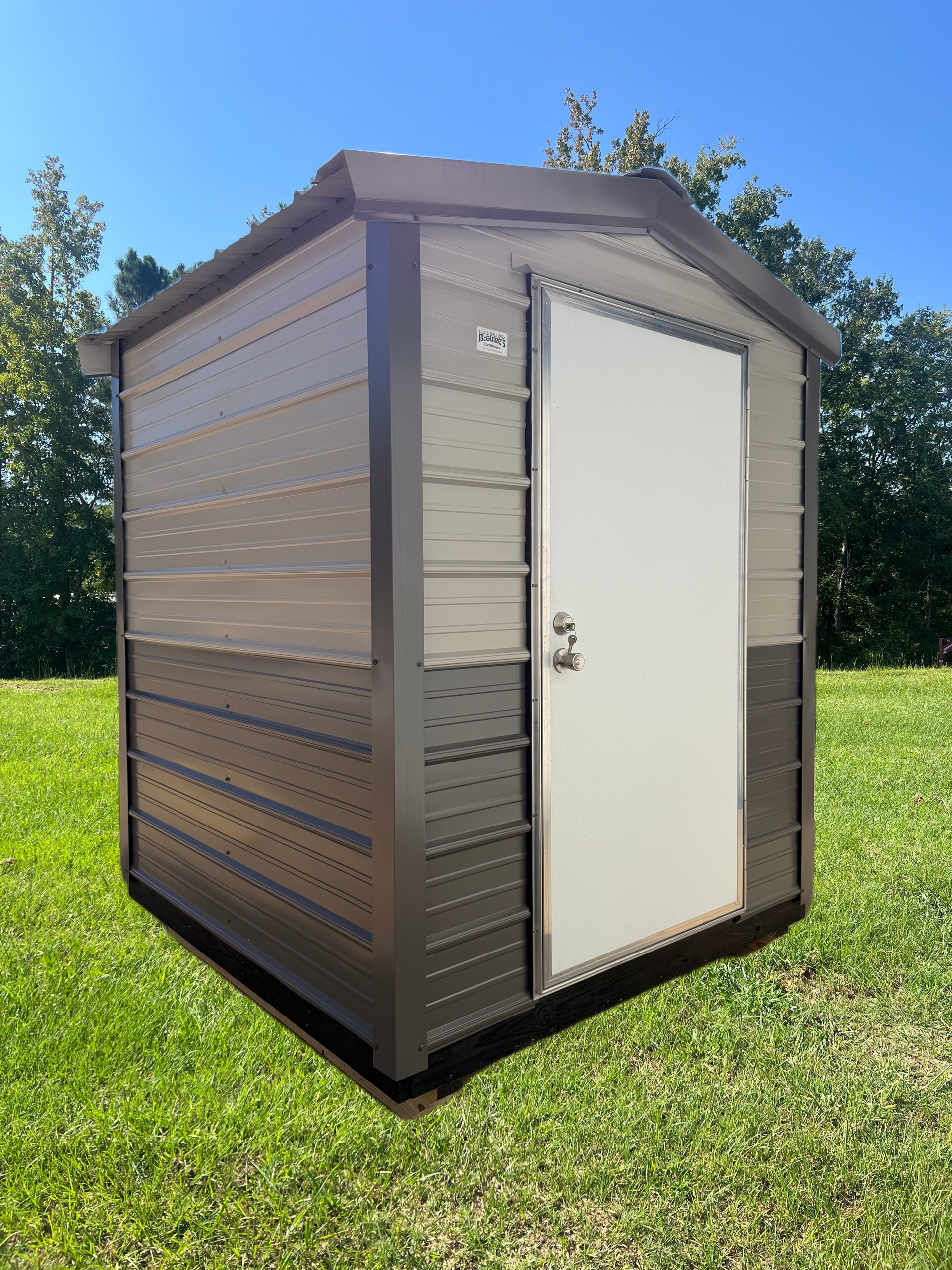 Small brown outdoor storage shed with a white door on a sunny grassy lawn.