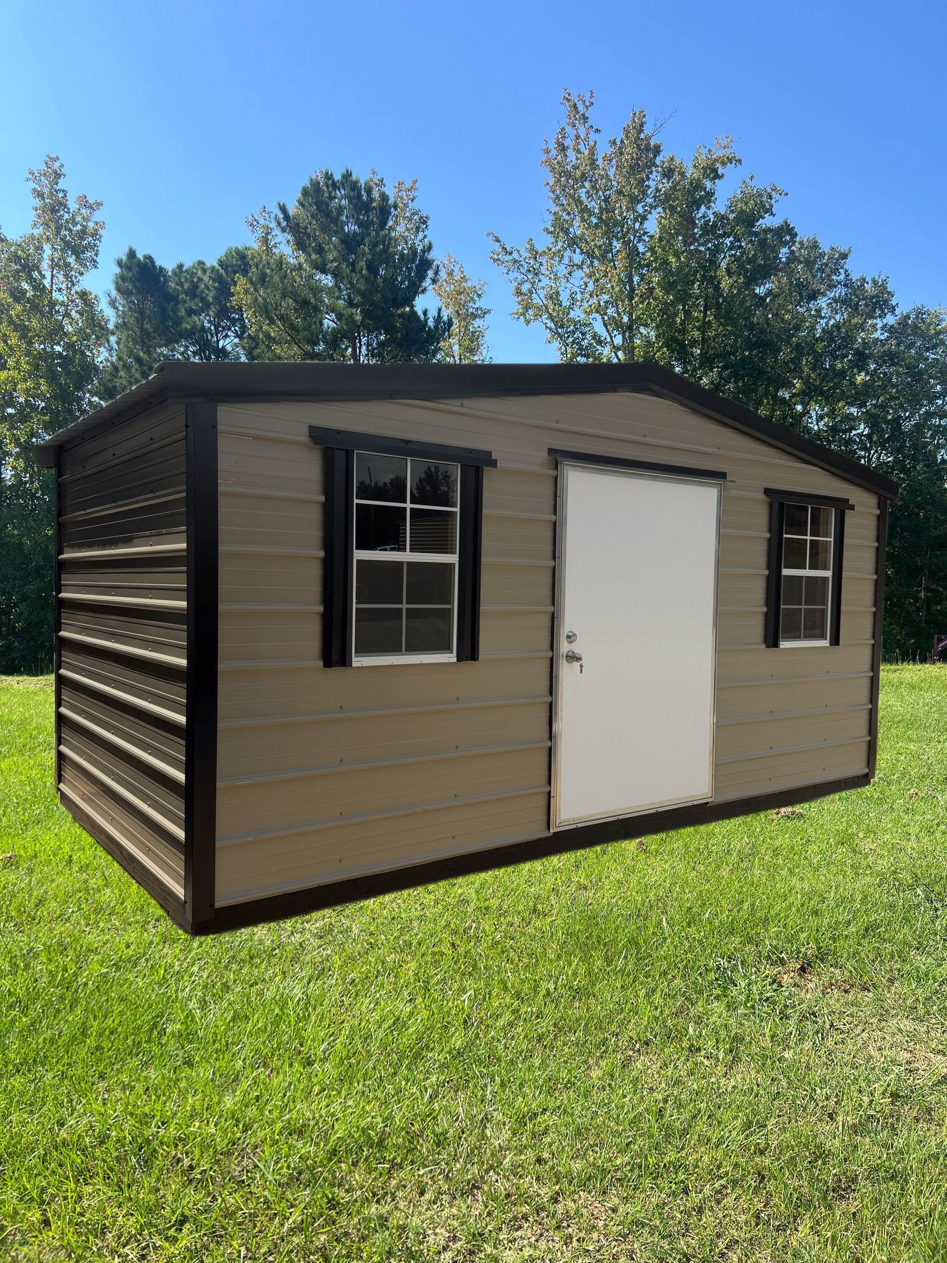 Small tan shed with white door and windows on a grassy lawn under a blue sky