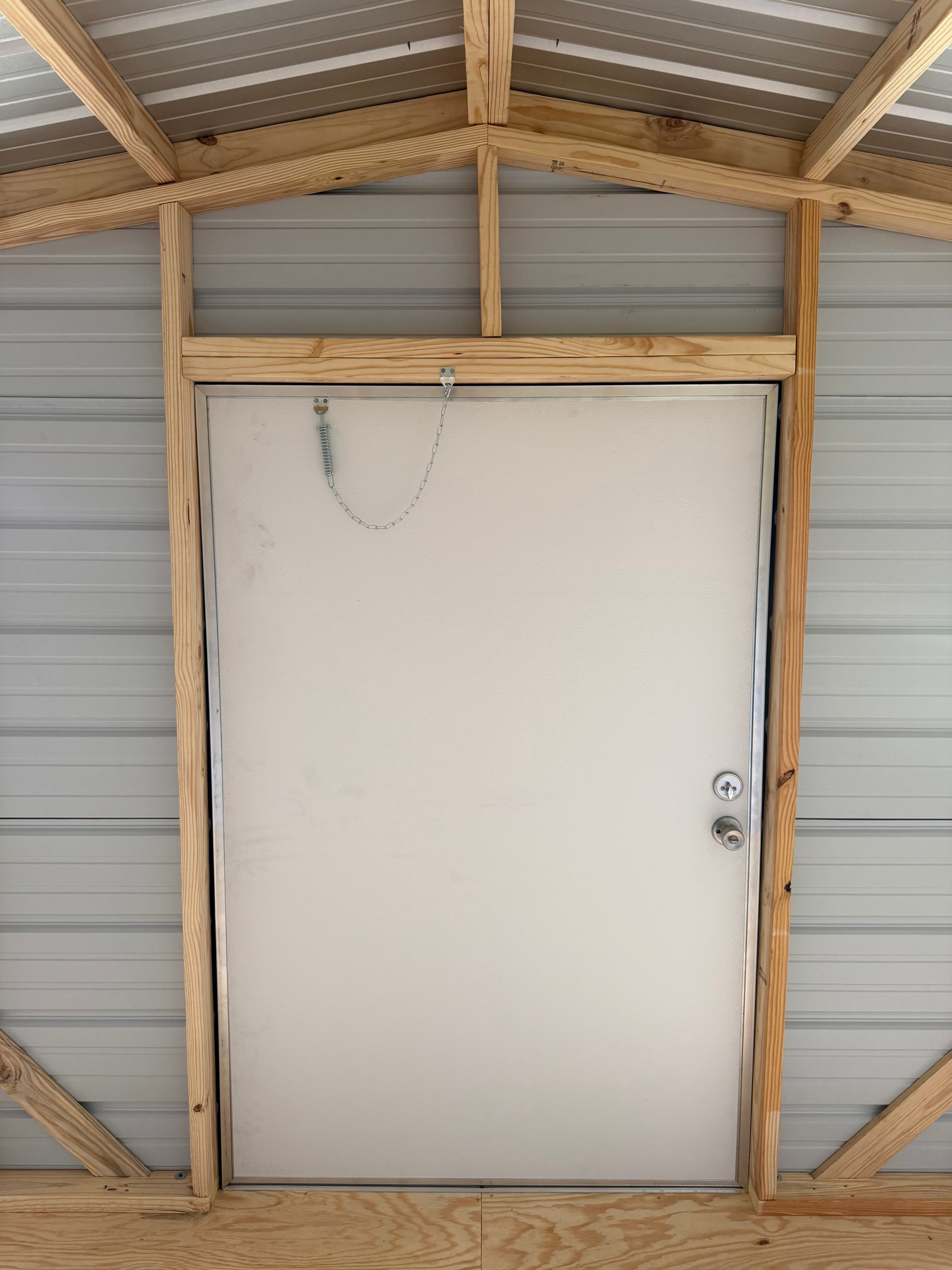 White door with a chain lock in a wooden frame inside a metal storage shed