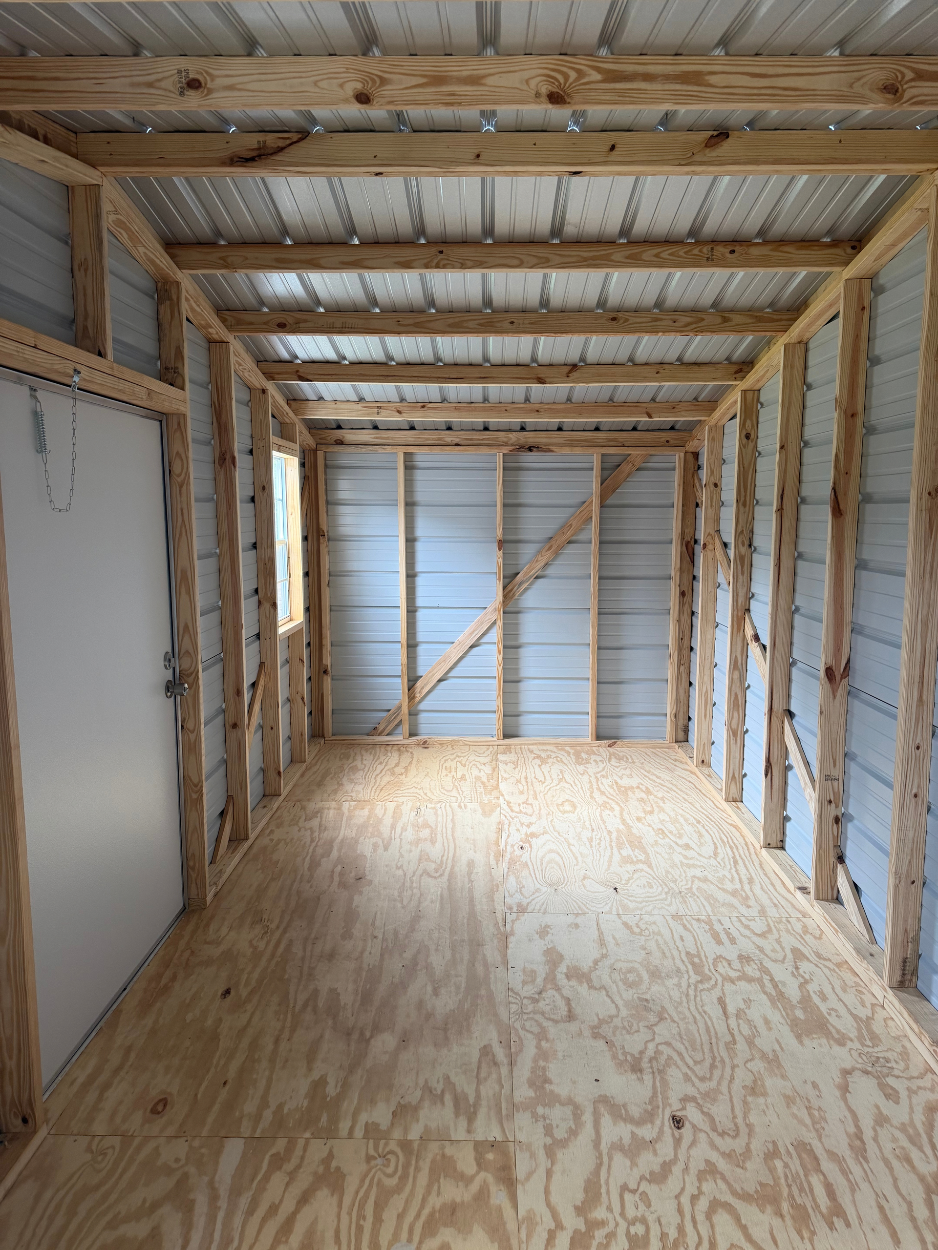Empty plywood-walled interior of a small wooden shed under construction