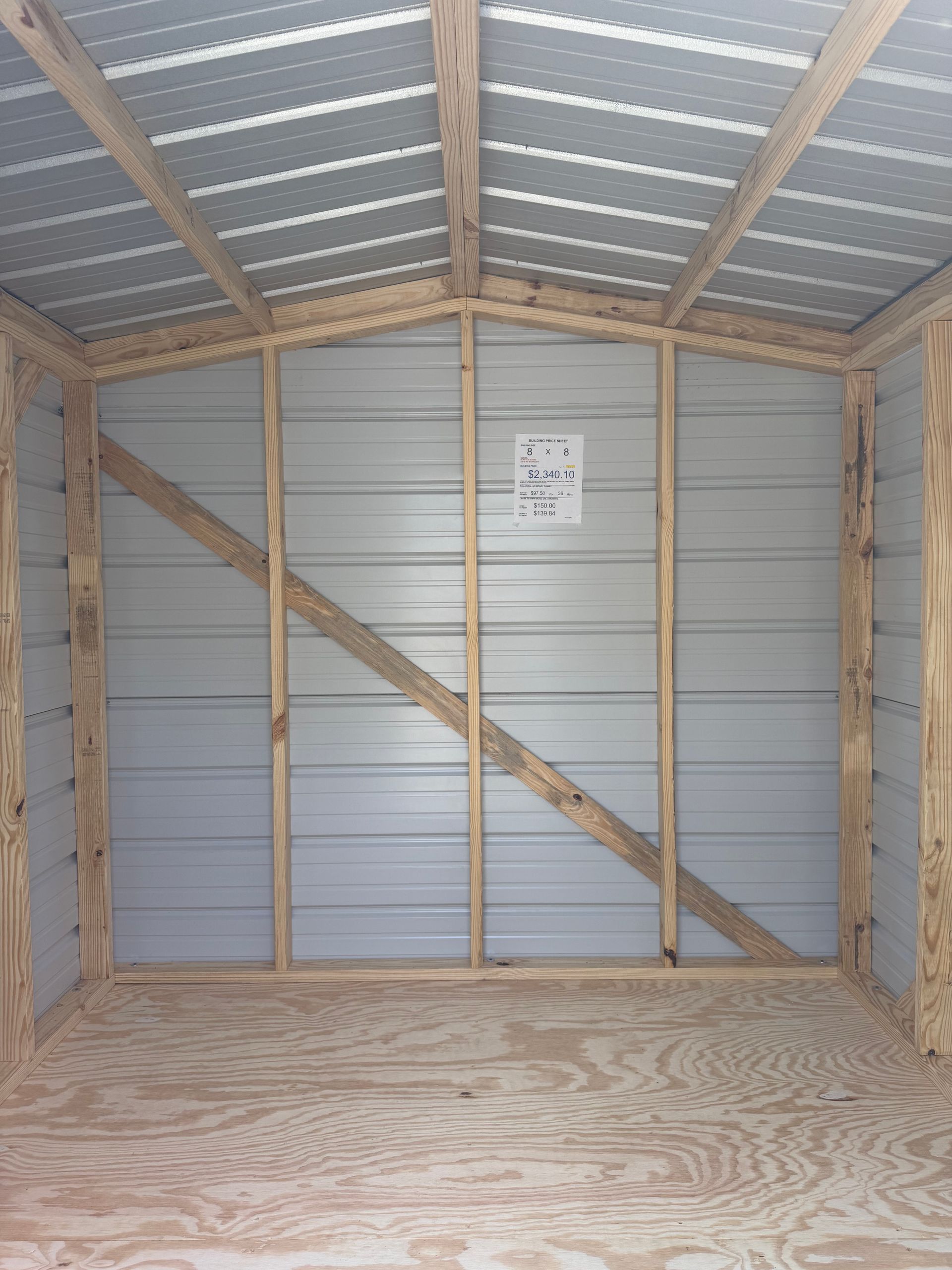 Interior of a small wooden shed with corrugated metal walls and a plywood floor.
