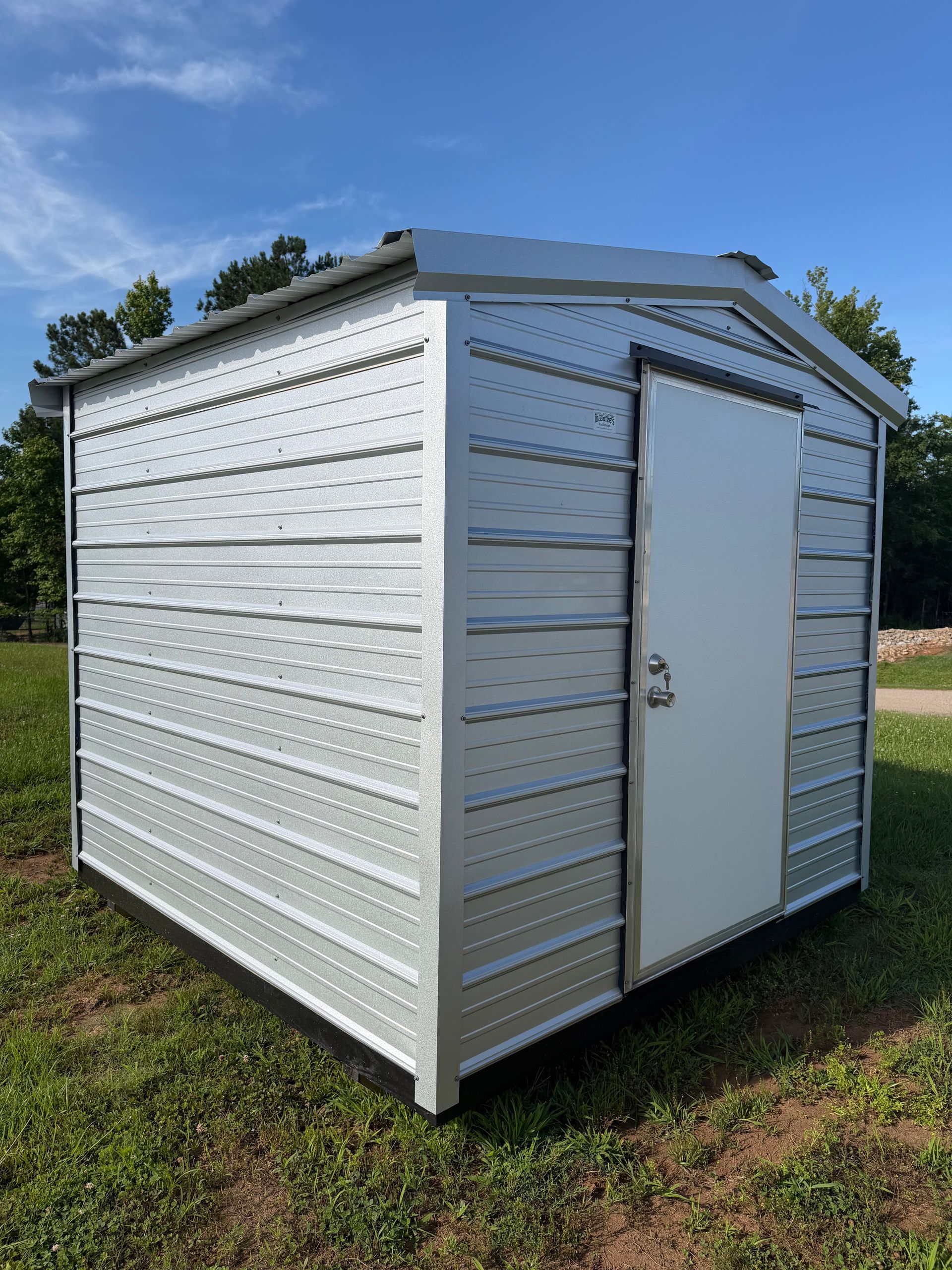 Small white-and-green outdoor storage shed on grass under a cloudy sky