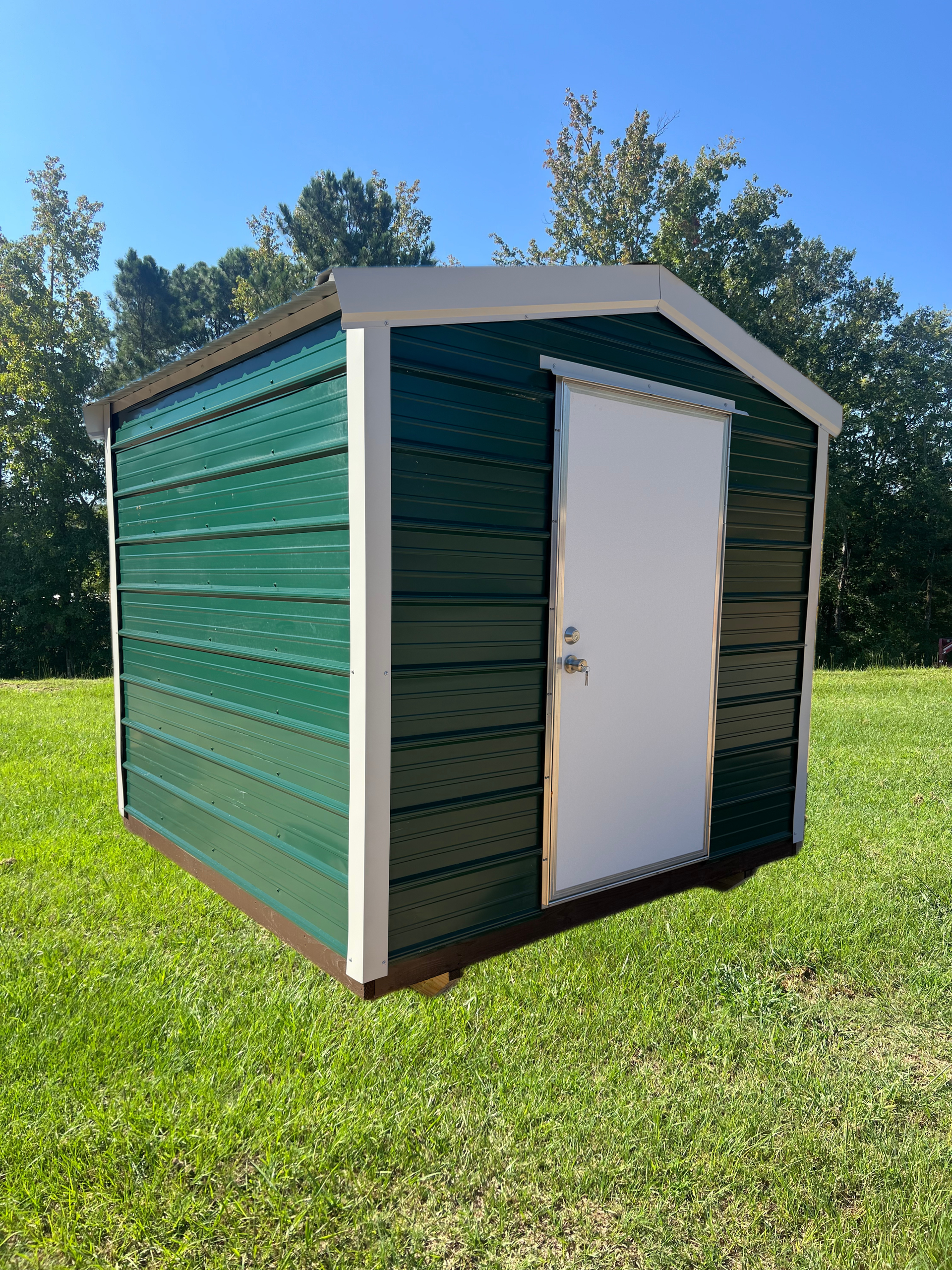 Green metal storage shed with white door on a grassy lawn under a blue sky