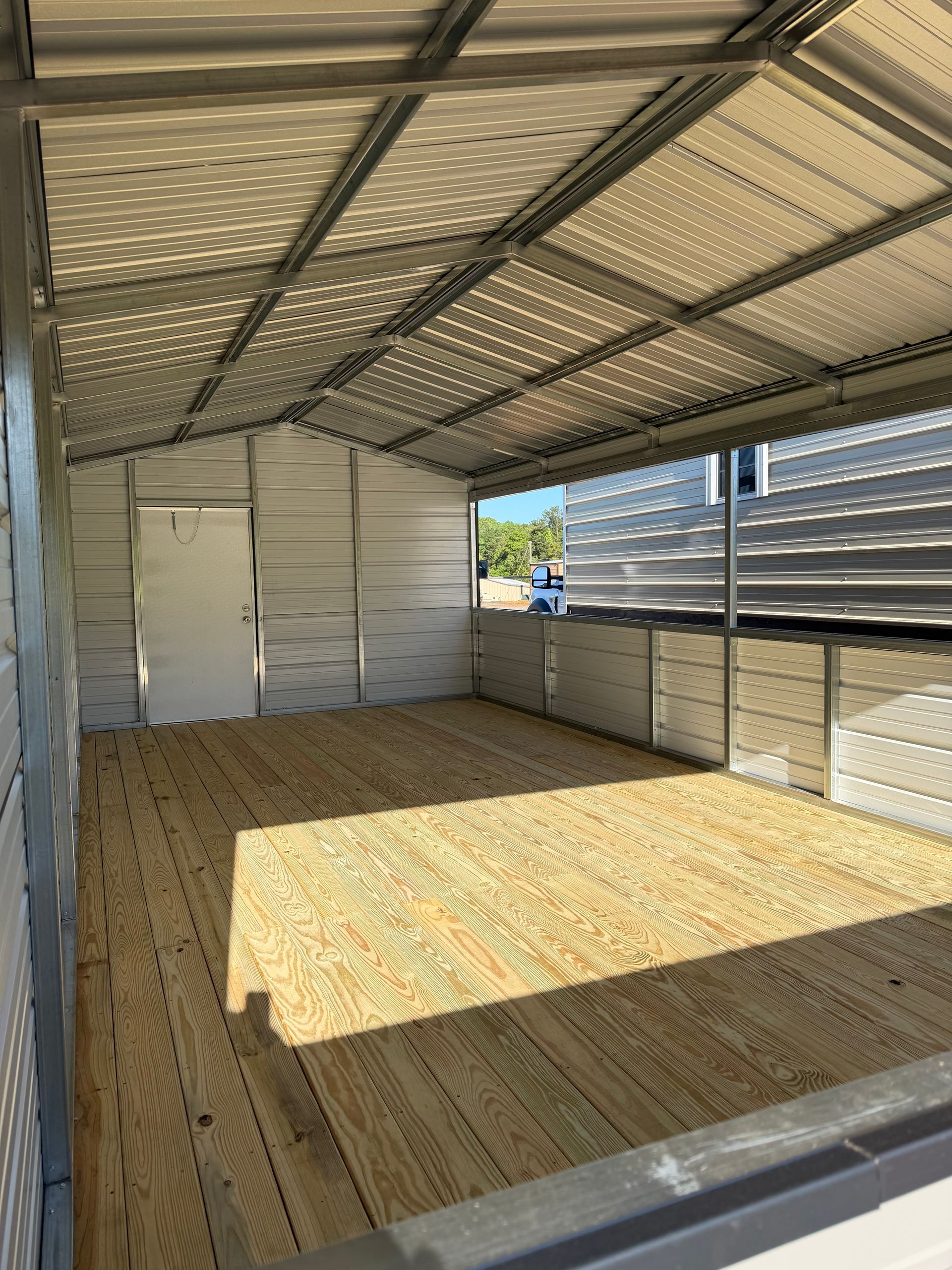 Empty livestock trailer with corrugated metal walls and a sunlit floor.