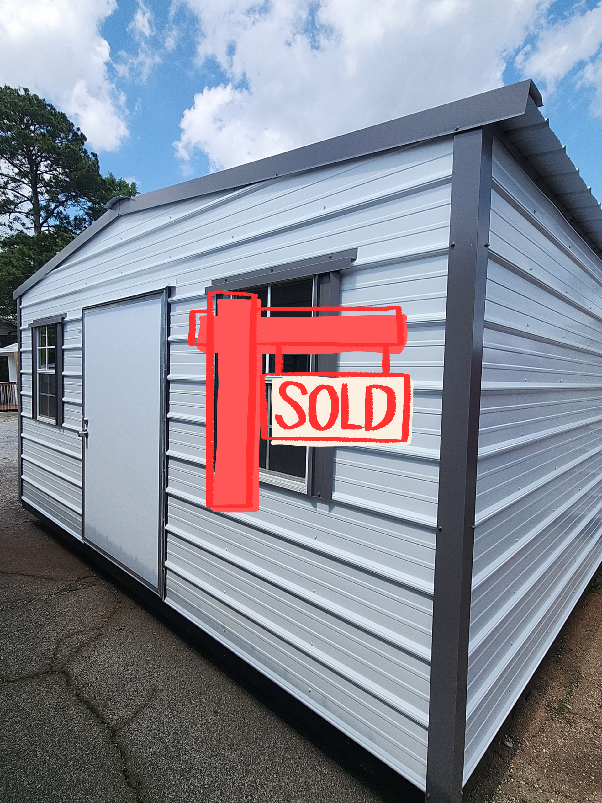 Metal mobile home exterior with a red “SOLD” sign posted on the side