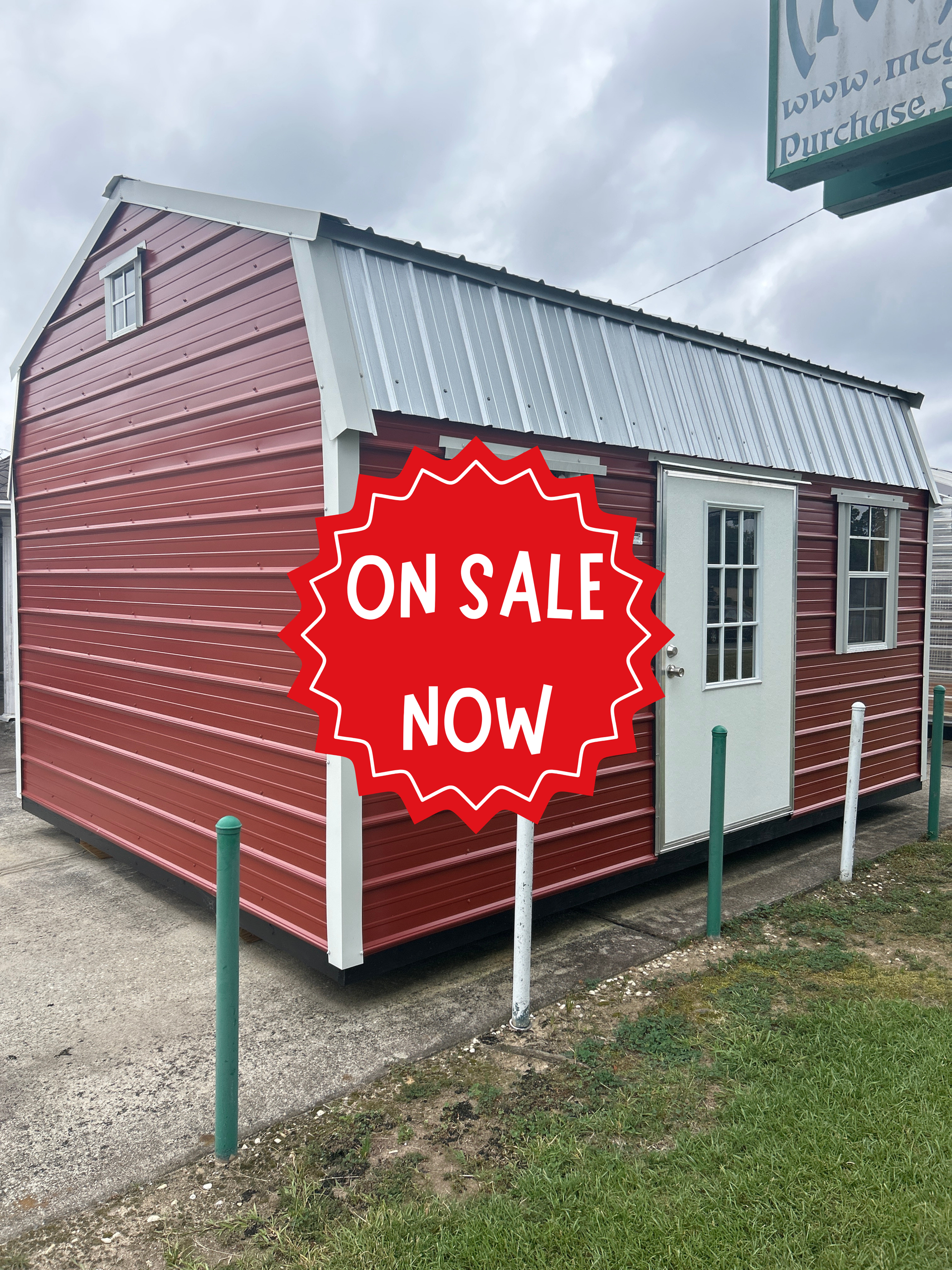 Red and white shed with a metal roof and an “ON SALE NOW” sign outdoors