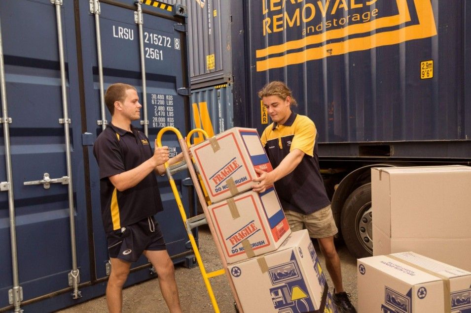 Two Men Are Carrying Boxes in Front of a Truck That Says Removals — Leader Removals & Storage in Brisbane, QLD