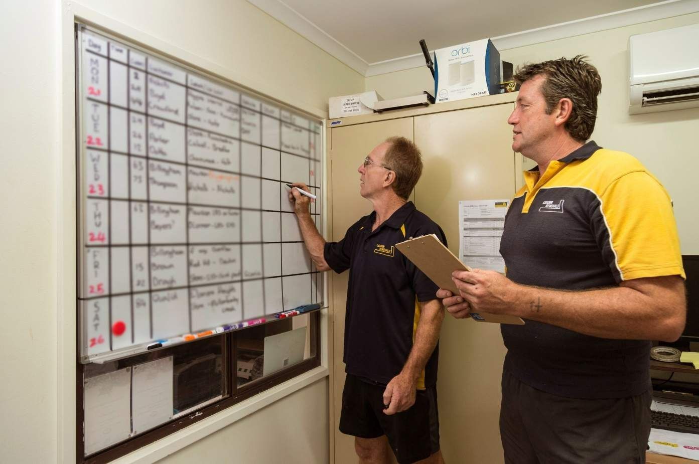 TwO Men Are Standing in Front of a Whiteboard Writing on It — Leader Removals & Storage in Melbourne, VIC