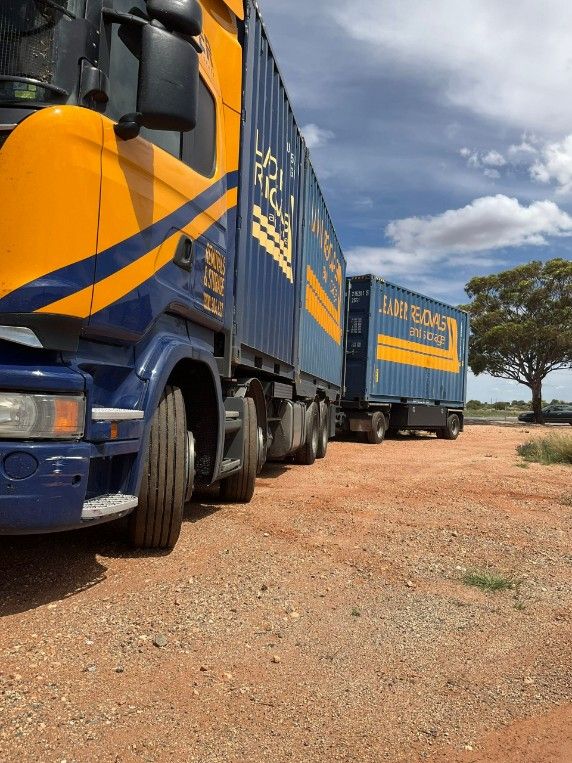 Two Trucks Are Parked Next to Each Other on a Dirt Road — Leader Removals & Storage in Melbourne, VIC