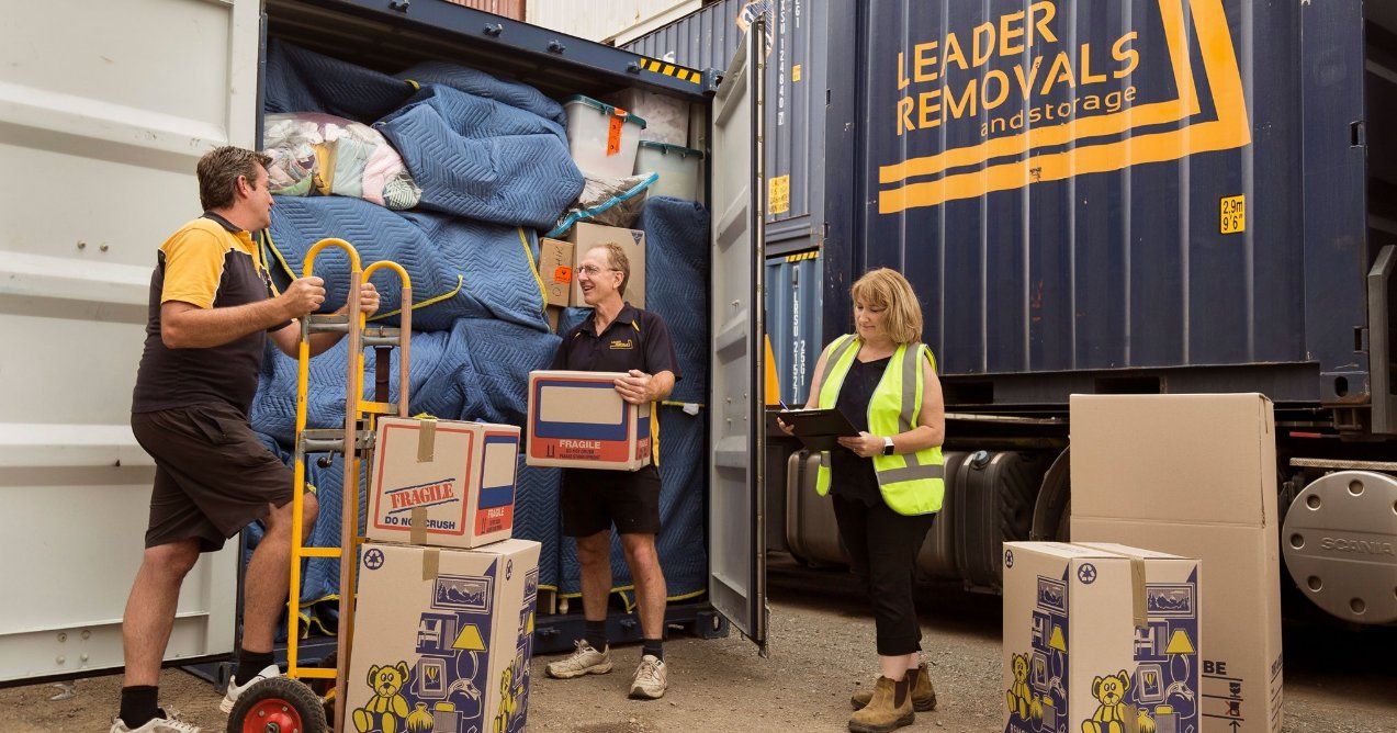 A Group of People Are Loading Boxes Into a Container — Leader Removals & Storage in Coffs Harbour, NSW