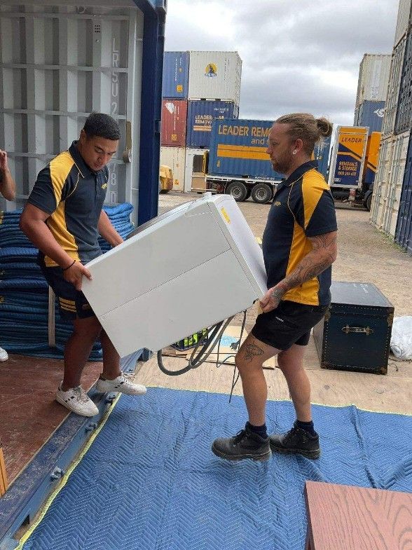 Two Men Are Carrying a Large White Box Into a Shipping Container — Leader Removals & Storage in Canberra, ACT