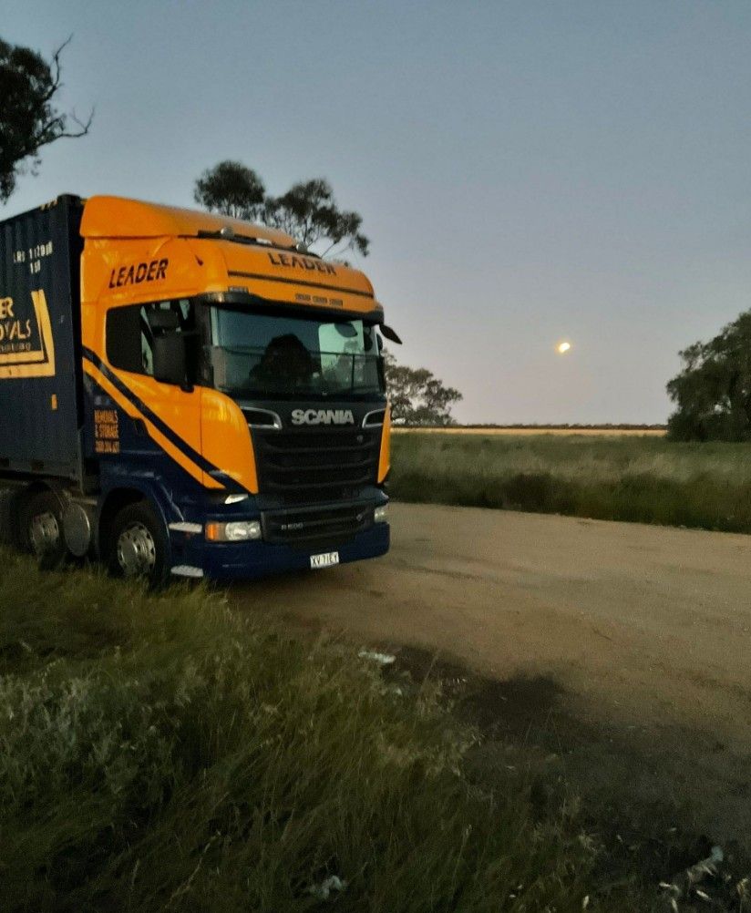 A Yellow and Blue Truck is Parked on the Side of the Road — Leader Removals & Storage in Gold Coast, QLD