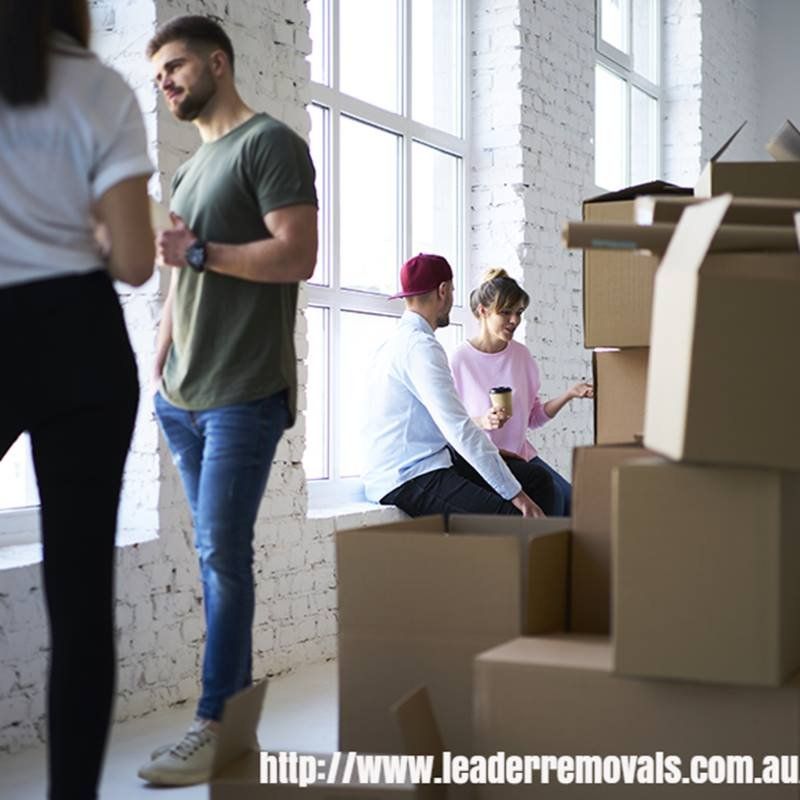 A Group of People Are Standing in A Room Surrounded by Cardboard Boxes — Leader Removals & Storage in Canberra, ACT