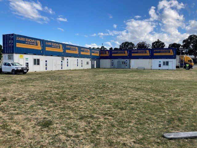 A Row of Shipping Containers Are Sitting on Top of A Lush Green Field — Leader Removals & Storage in Port Macquarie, NSW