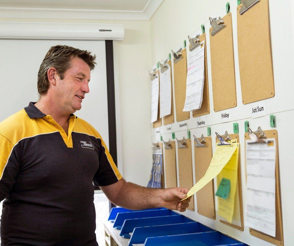 A Man in A Yellow and Black Shirt Is Holding a Piece of Paper — Leader Removals & Storage in Canberra, ACT