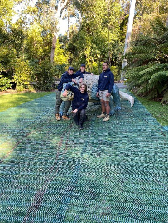 A Group of People Are Posing for A Picture in Front of A Dinosaur Statue — Leader Removals & Storage in Canberra, ACT
