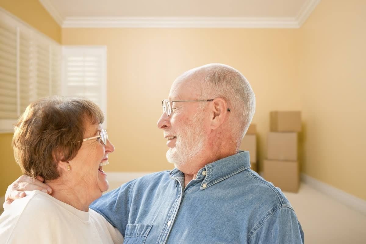 An Elderly Couple Standing Next to Each Other in A Room with Boxes — Leader Removals & Storage in Canberra, ACT