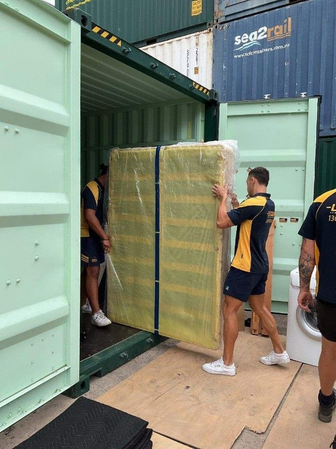 A Man is Carrying a Mattress Into a Shipping Container — Leader Removals & Storage in Canberra, ACT
