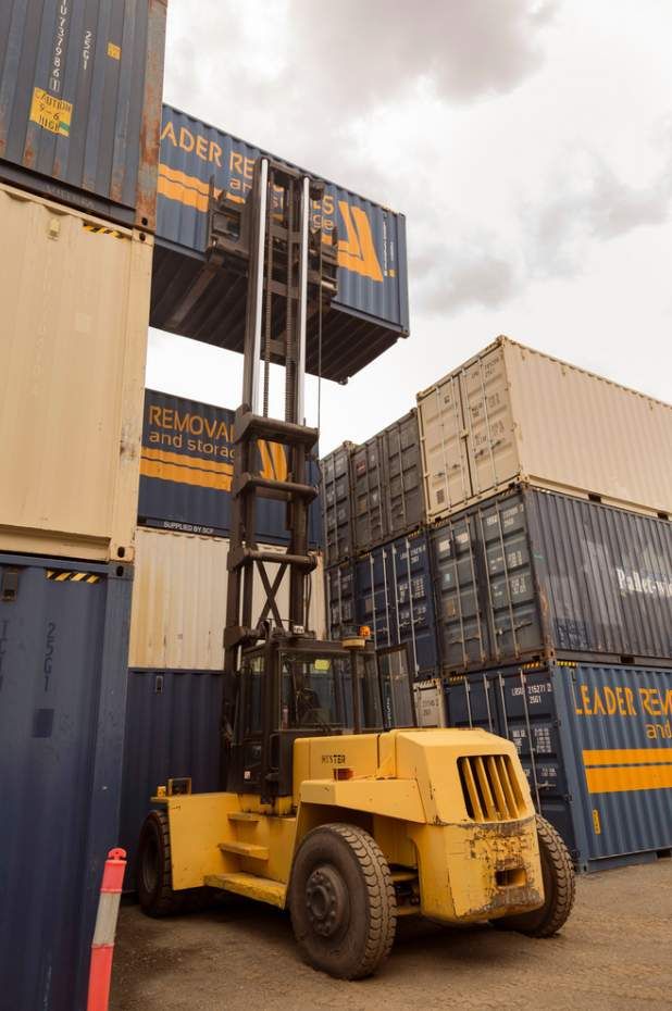 A Yellow Forklift is Moving a Stack of Shipping Containers — Leader Removals & Storage in Wagga Wagga, NSW