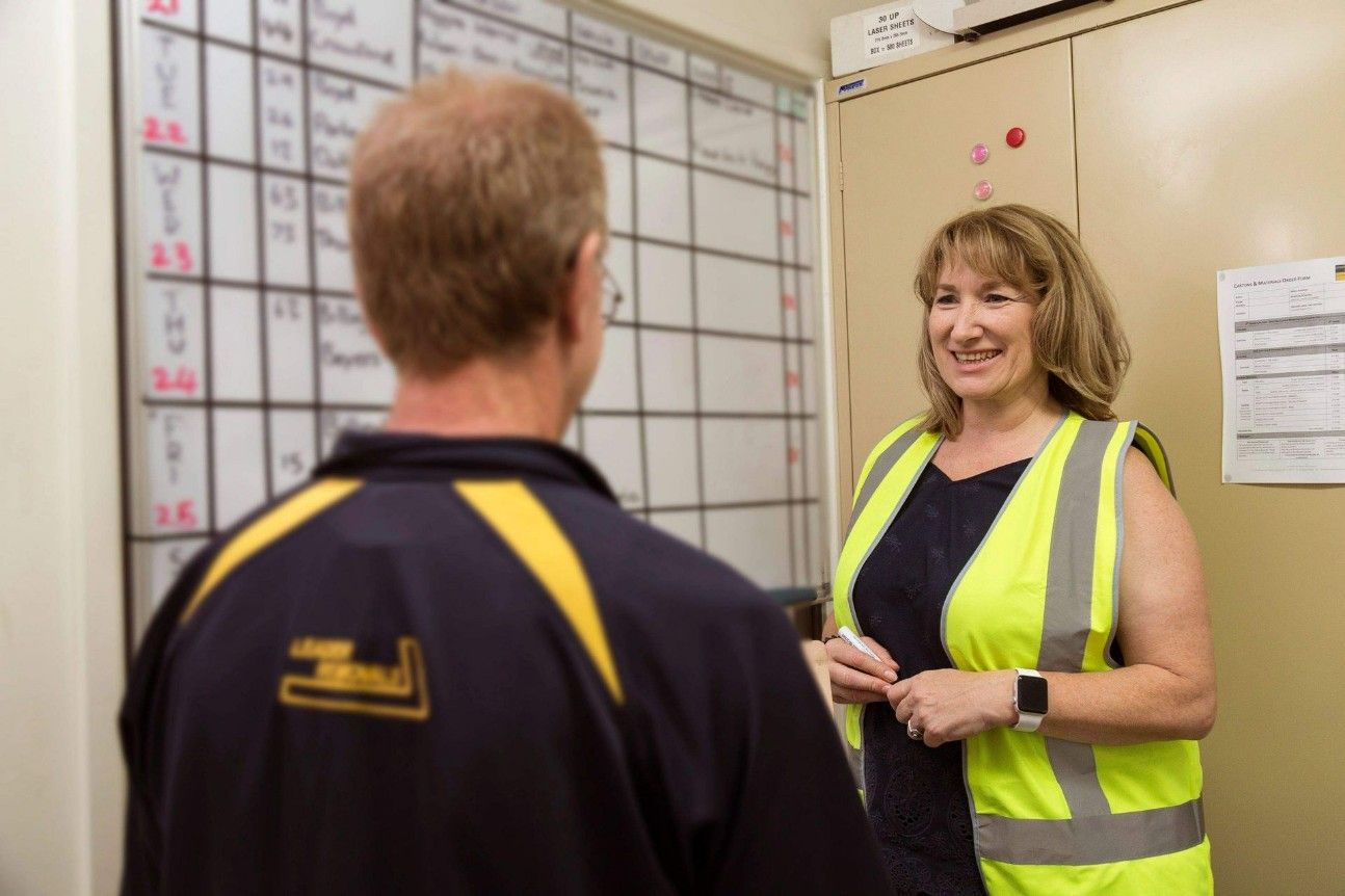 A Woman in a Yellow Vest is Talking to a Man in a Black Shirt — Leader Removals & Storage in Canberra, ACT