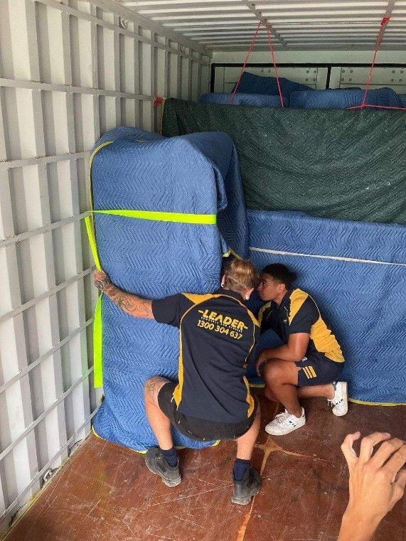 A Man and a Woman Are Measuring a Piece of Furniture in a Container — Leader Removals & Storage in Coffs Harbour, NSW