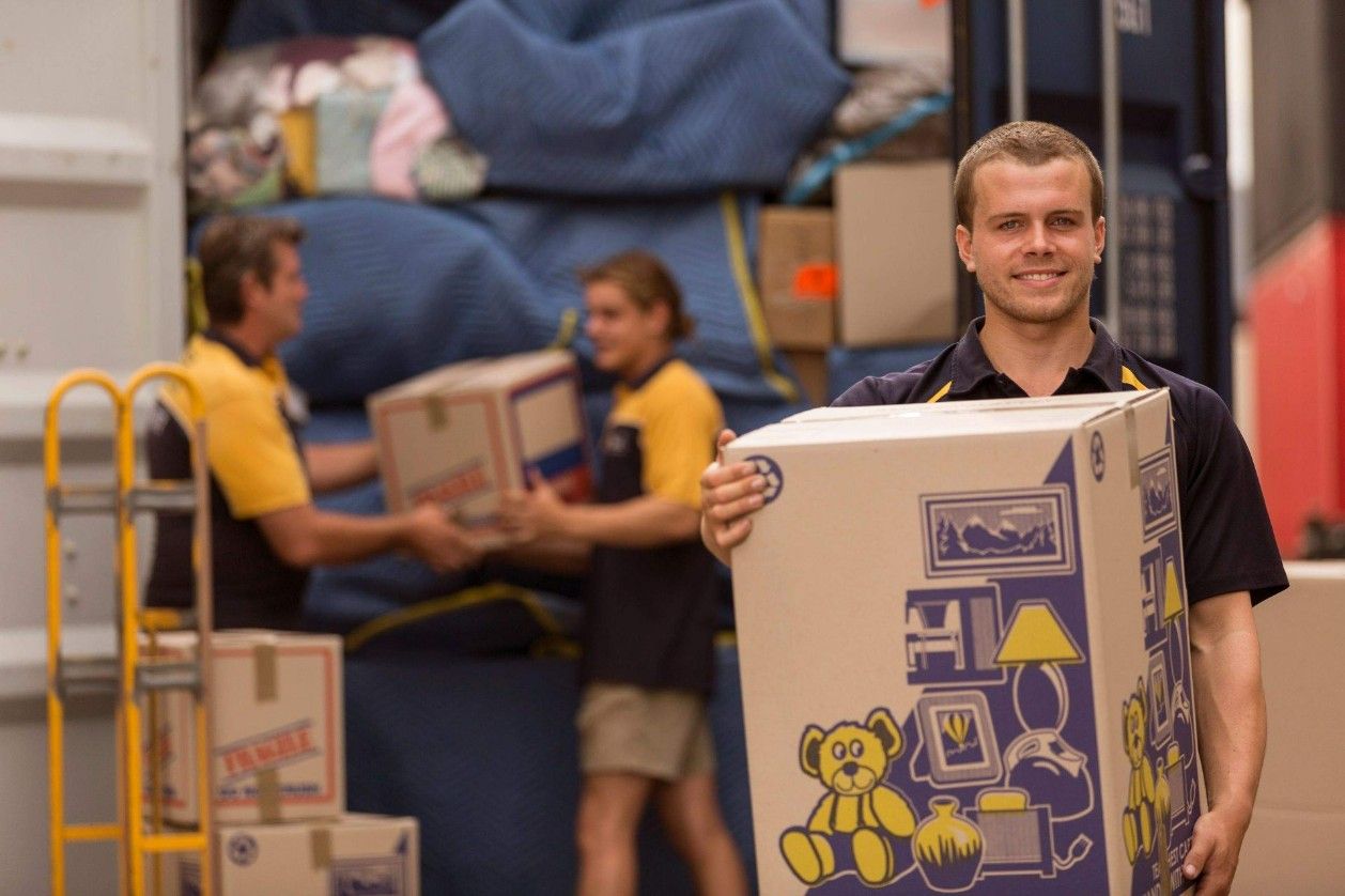 A Man is Holding a Box With a Teddy Bear on It — Leader Removals & Storage in Mitchell, ACT