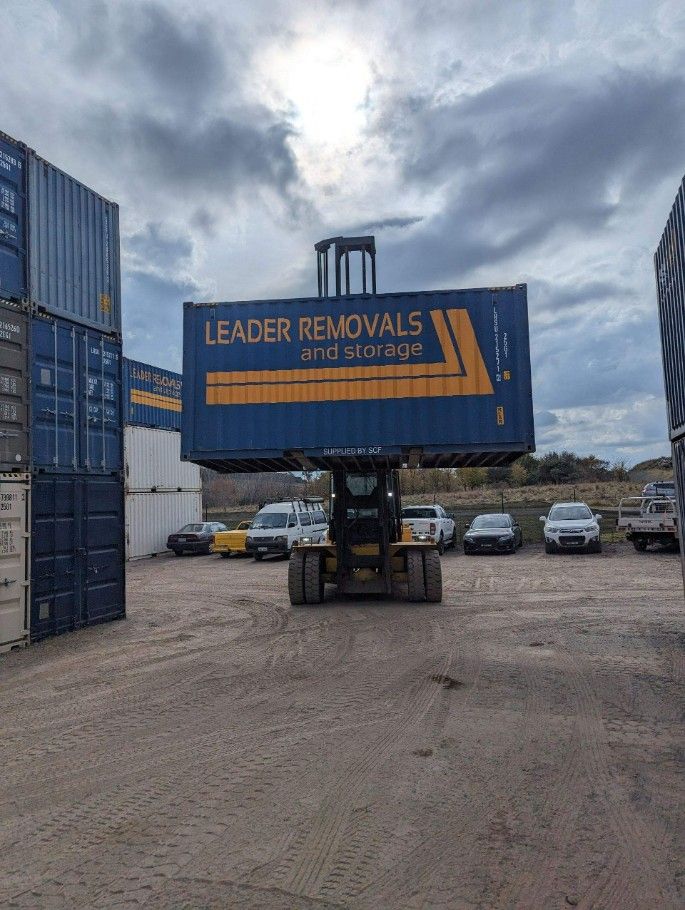 A Large Blue Container is Being Lifted by a Forklift in a Parking Lot — Leader Removals & Storage in Bowral, NSW