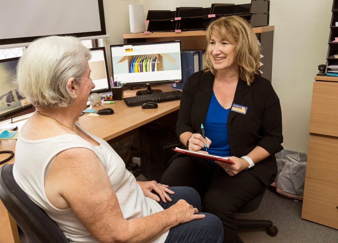 A Woman Is Sitting at A Desk Talking to An Older Woman — Leader Removals & Storage in Mitchell, ACT
