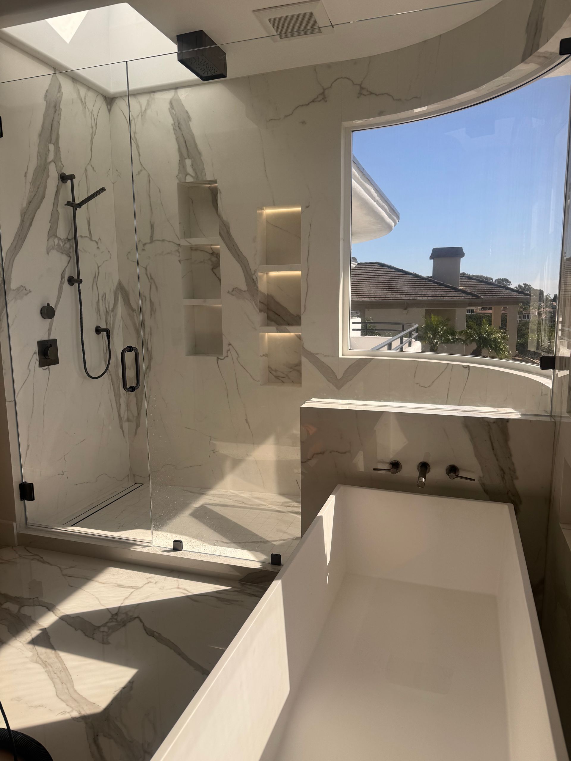 Luxurious bathroom with marble shower, soaking tub, and outside view.