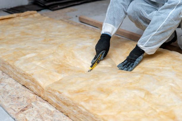 Professional workman installing thermal insulation layer with fiberglass wool.