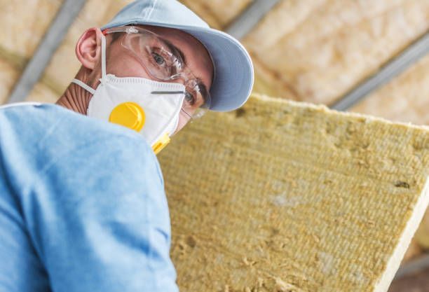 A man wearing a mask and glasses is holding a piece of rock wool.