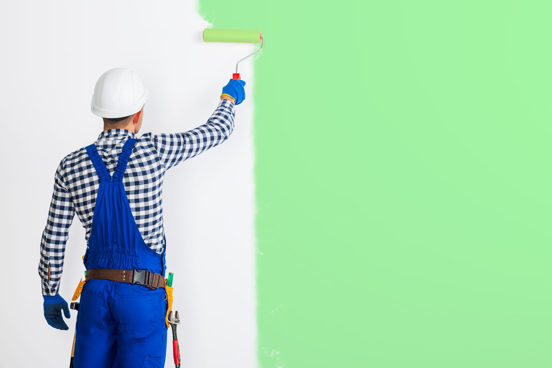 A man is painting a wall with a paint roller.