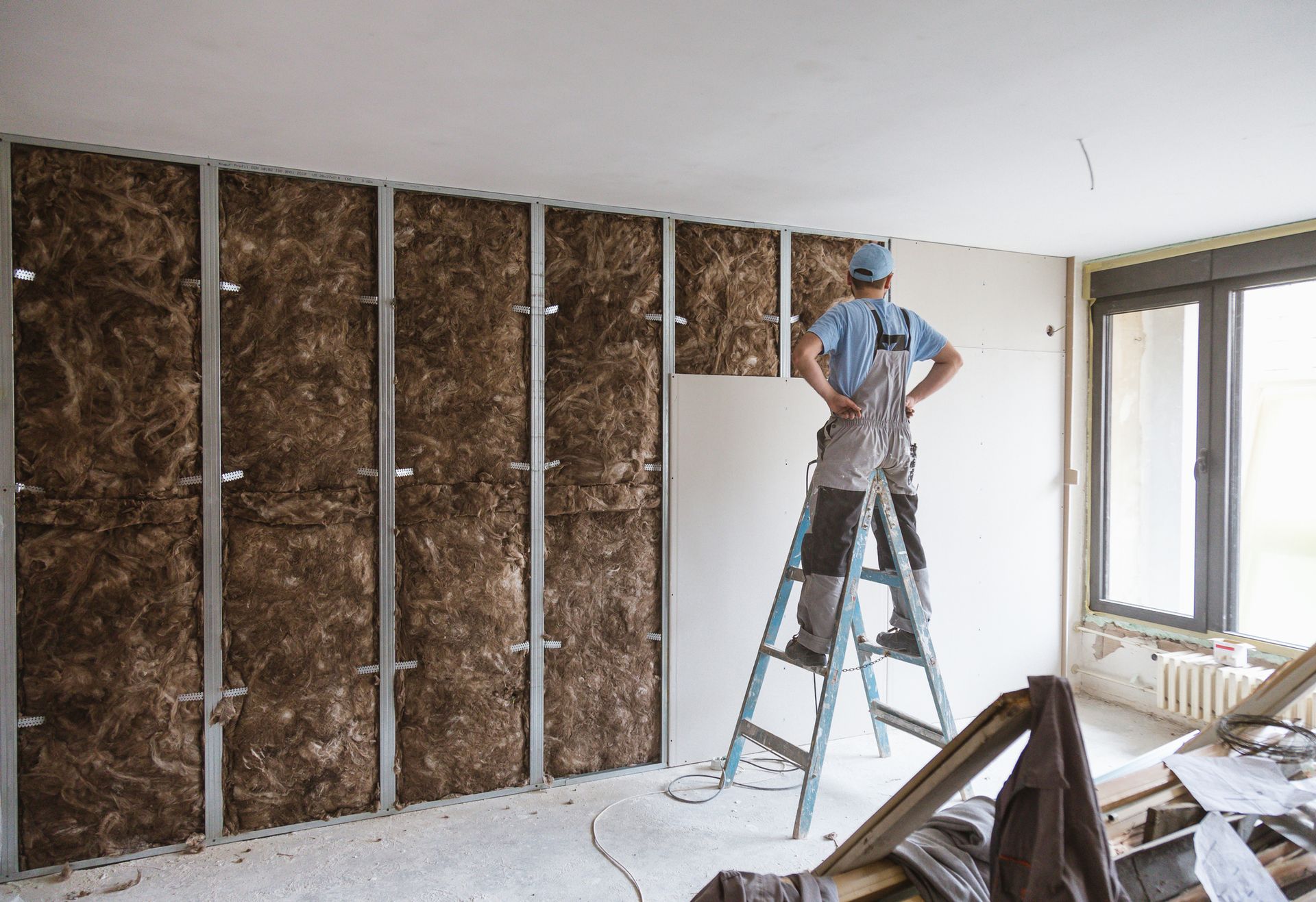 A man is standing on a ladder in a room.